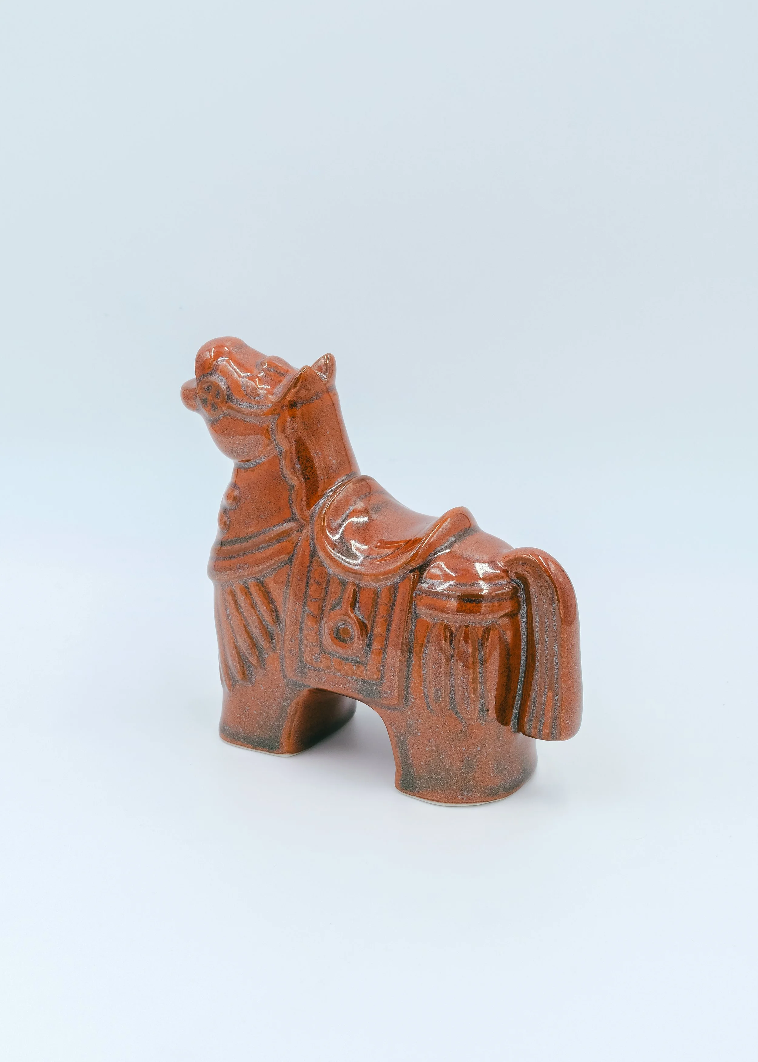 Hand-painted brown glazed pottery horse with traditional saddle relief design.