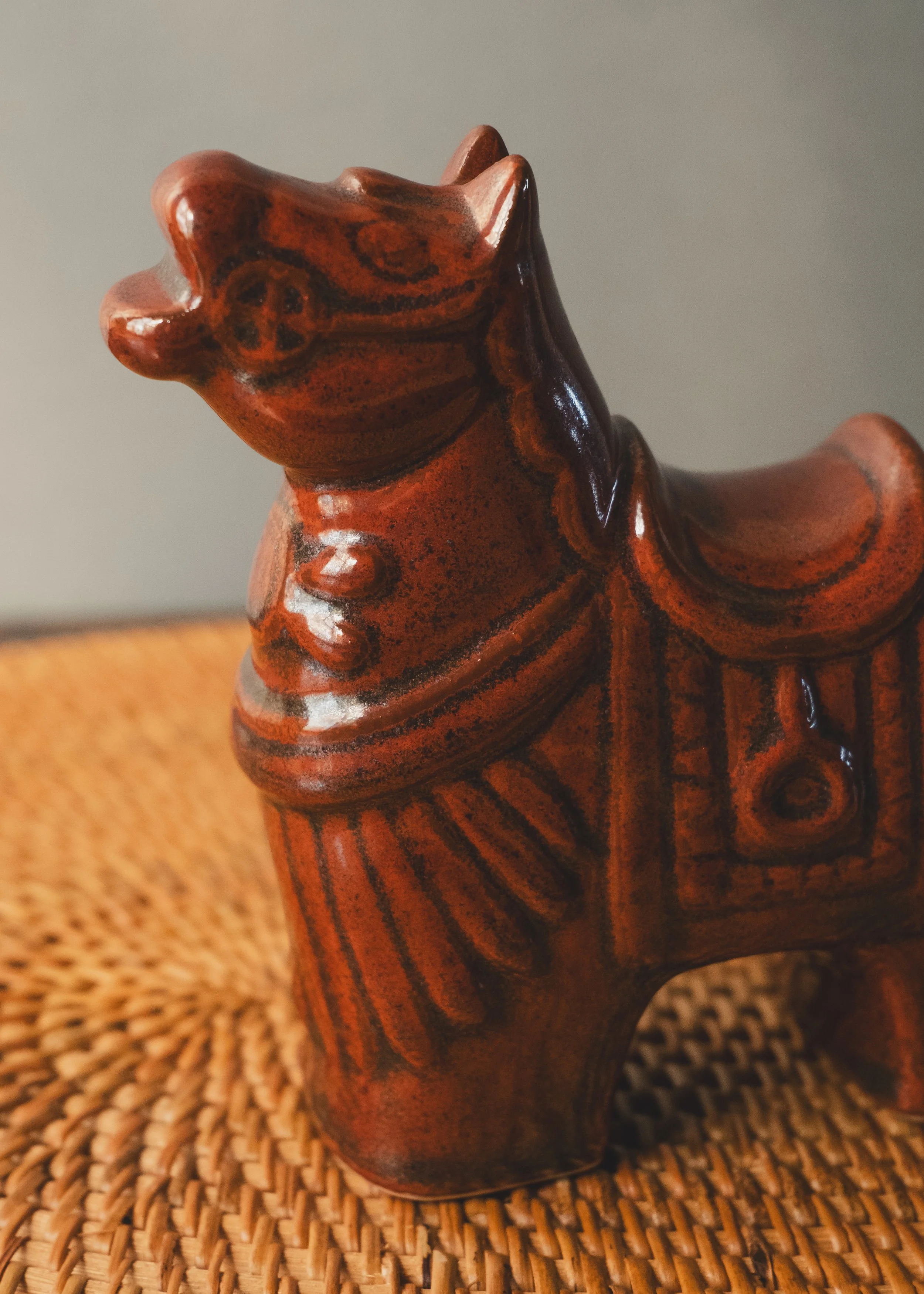 Close up detail of iron-amber glazed ceramic texture with vermilion painted accents.