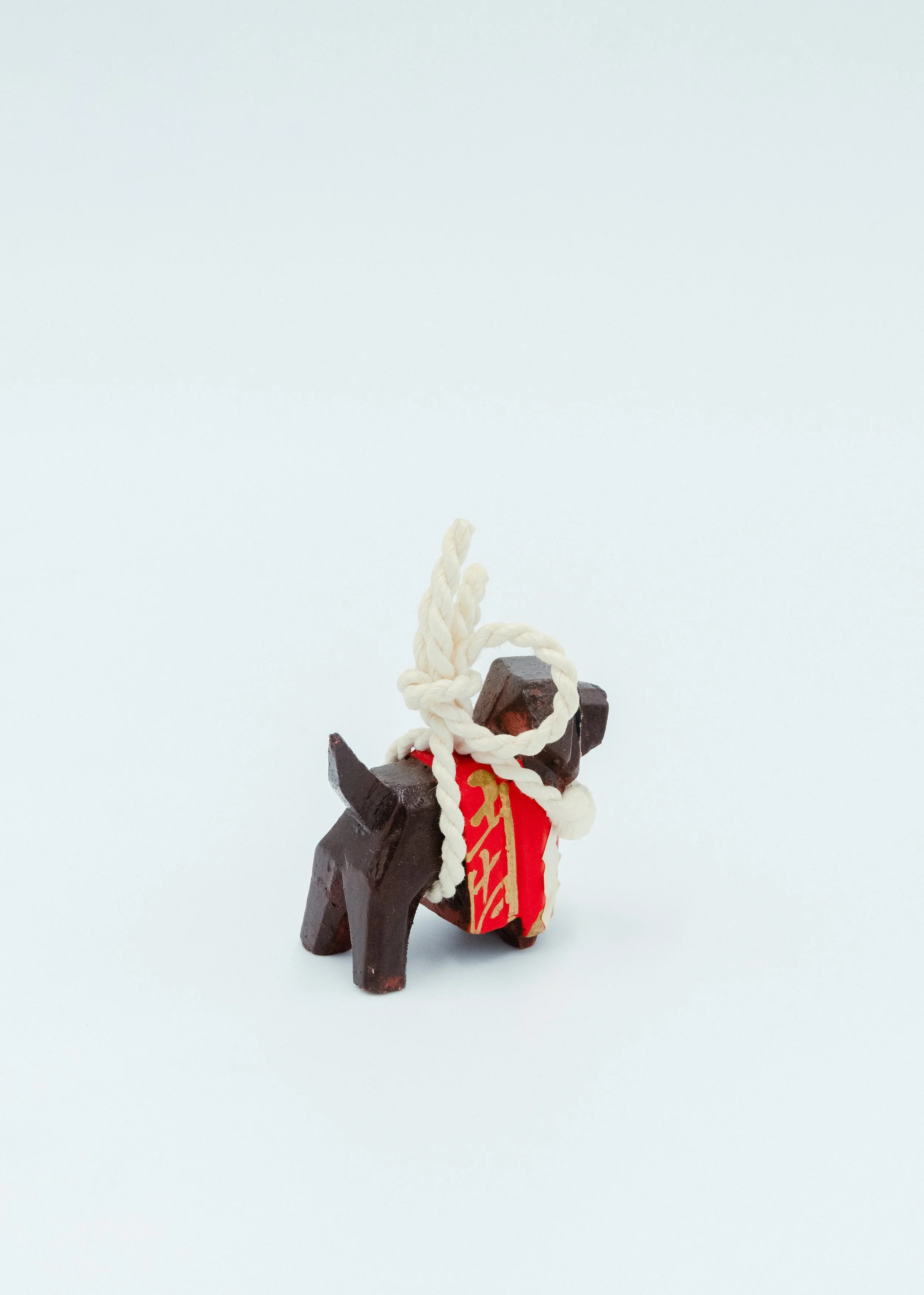Back view of vintage wooden Tosa dog sculpture wearing ceremonial Sumo rope shimenawa Japanese folk art