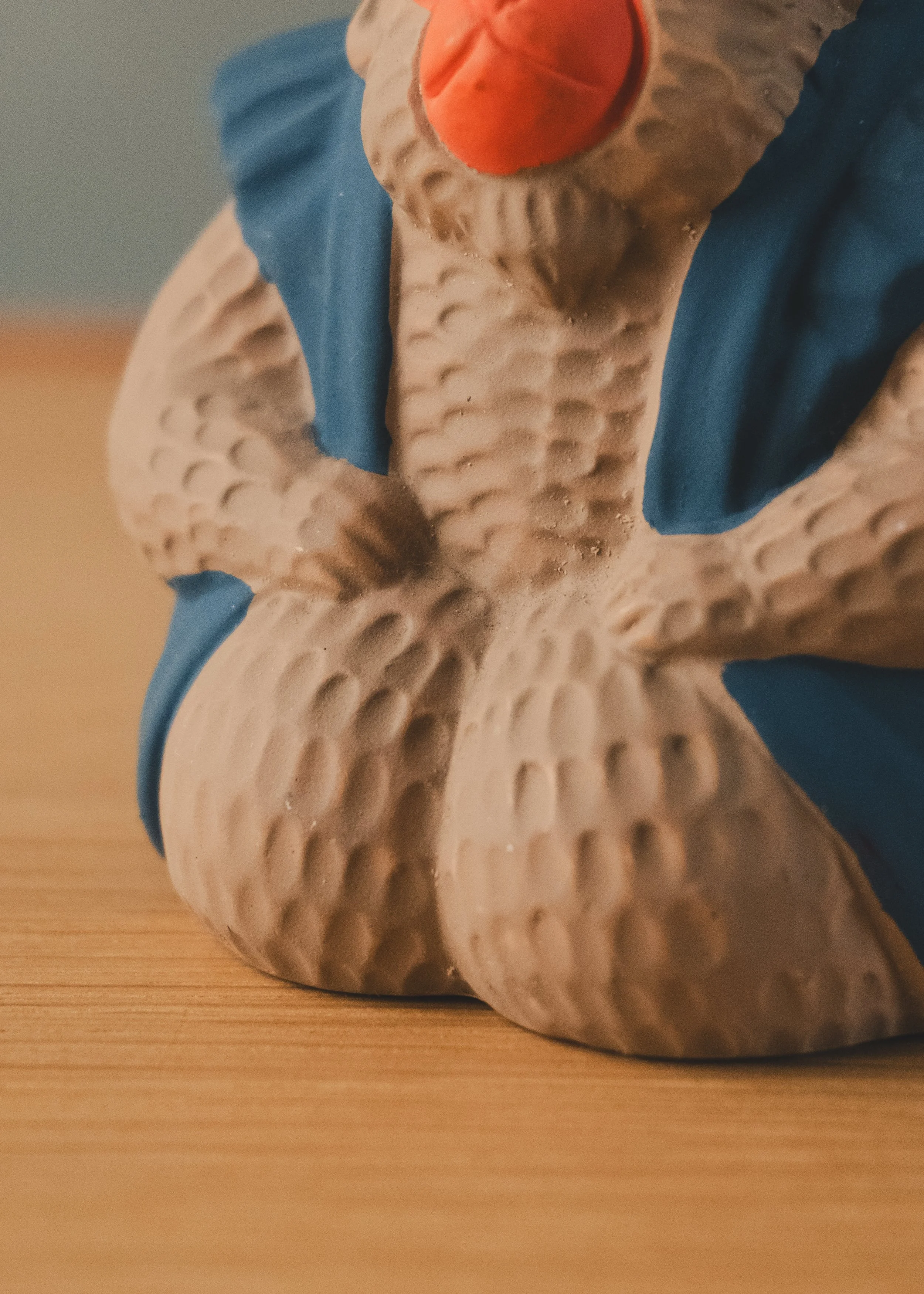 Detailed hand-finished texture on an unglazed cast clay monkey talisman from Japan. Showcasing the chiseled physical narrative of a sacred shrine artifact.