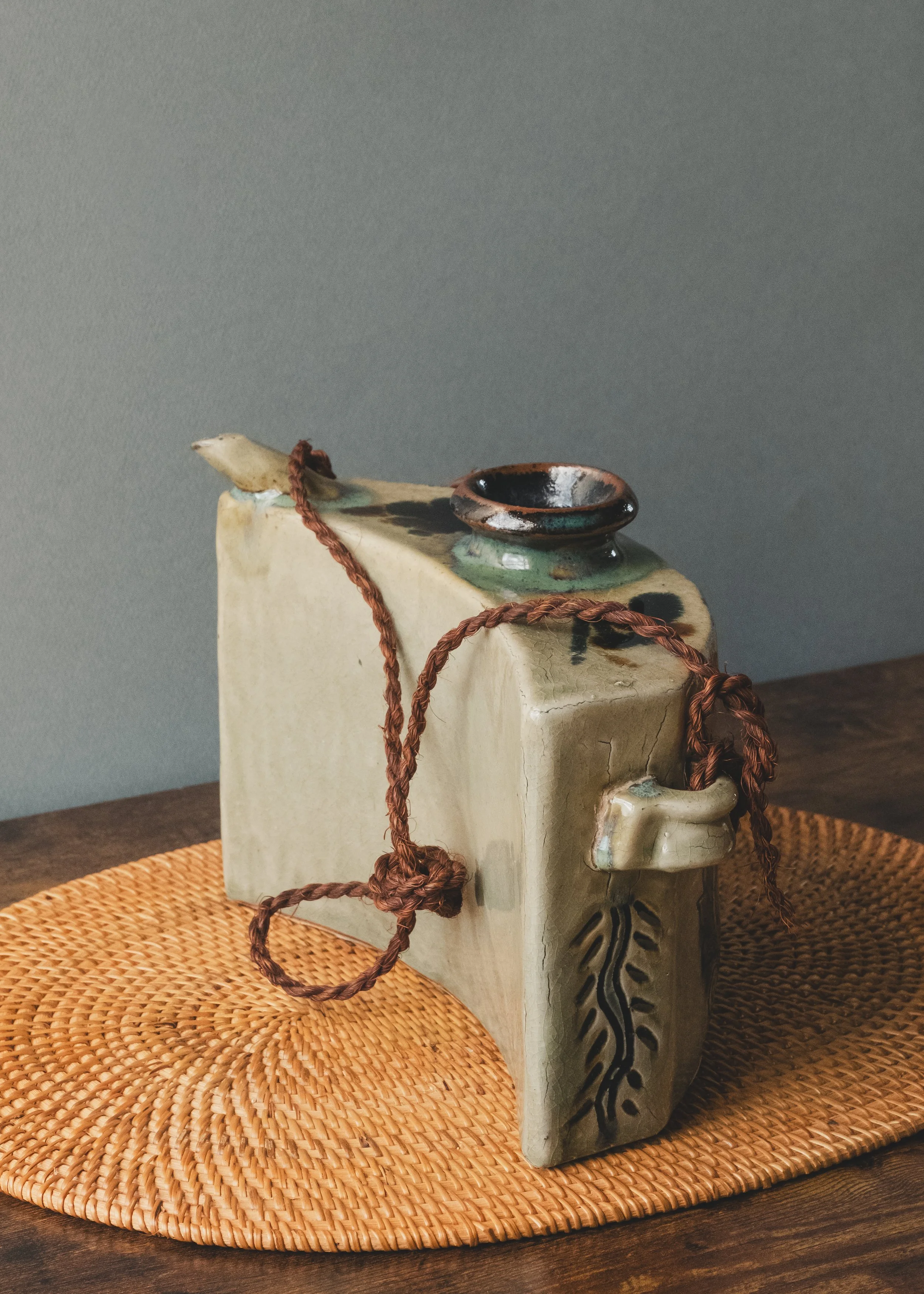 Profile view of a Japanese handmade clay bell (Tsuchi-rei) showing the ergonomic curved structure for portable use.