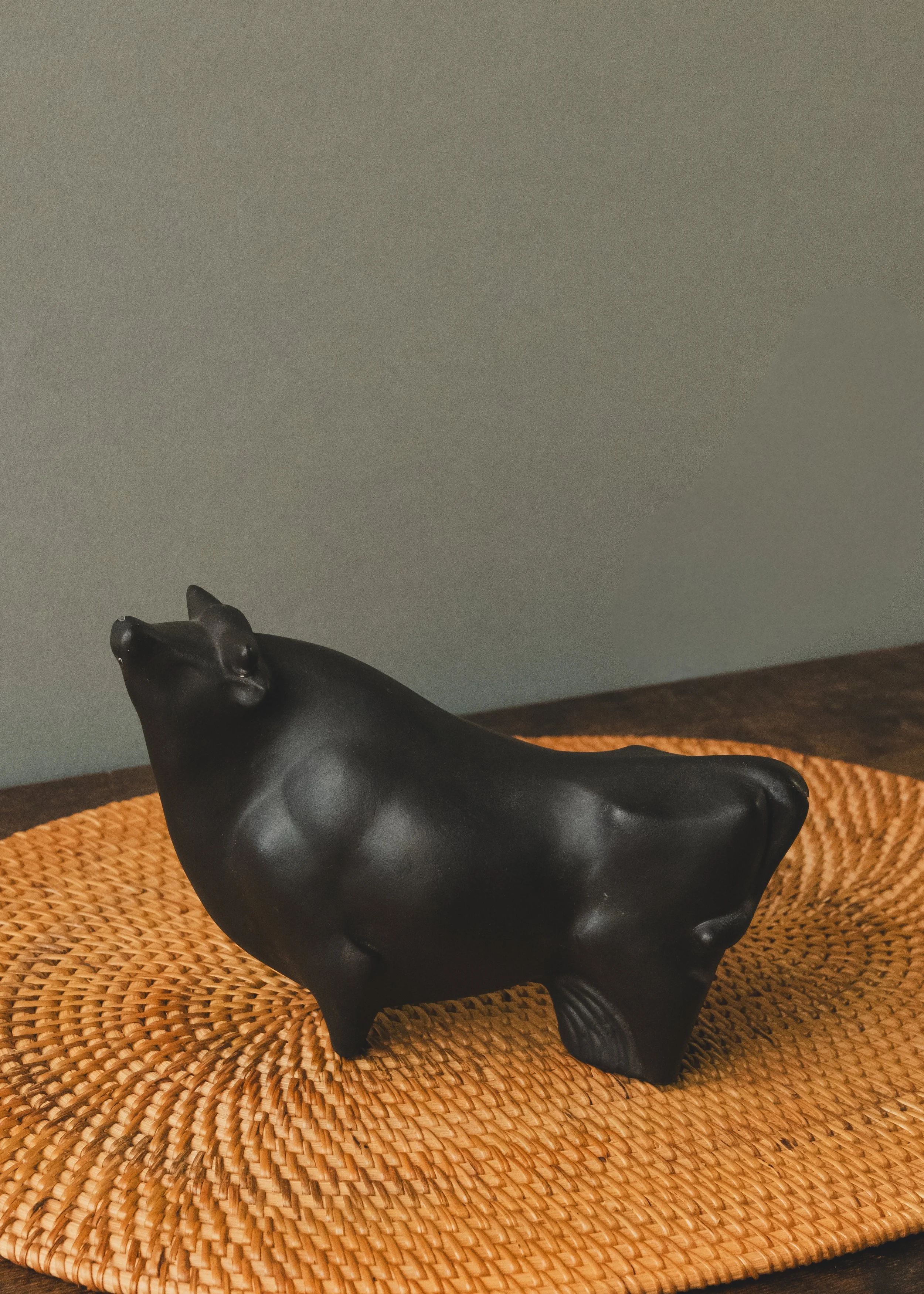 Side profile of an anonymous Japanese black bull figurine. A mid-century minimalist decor piece featuring deep, light-absorbing matte glaze and a grounded, authoritative stance.