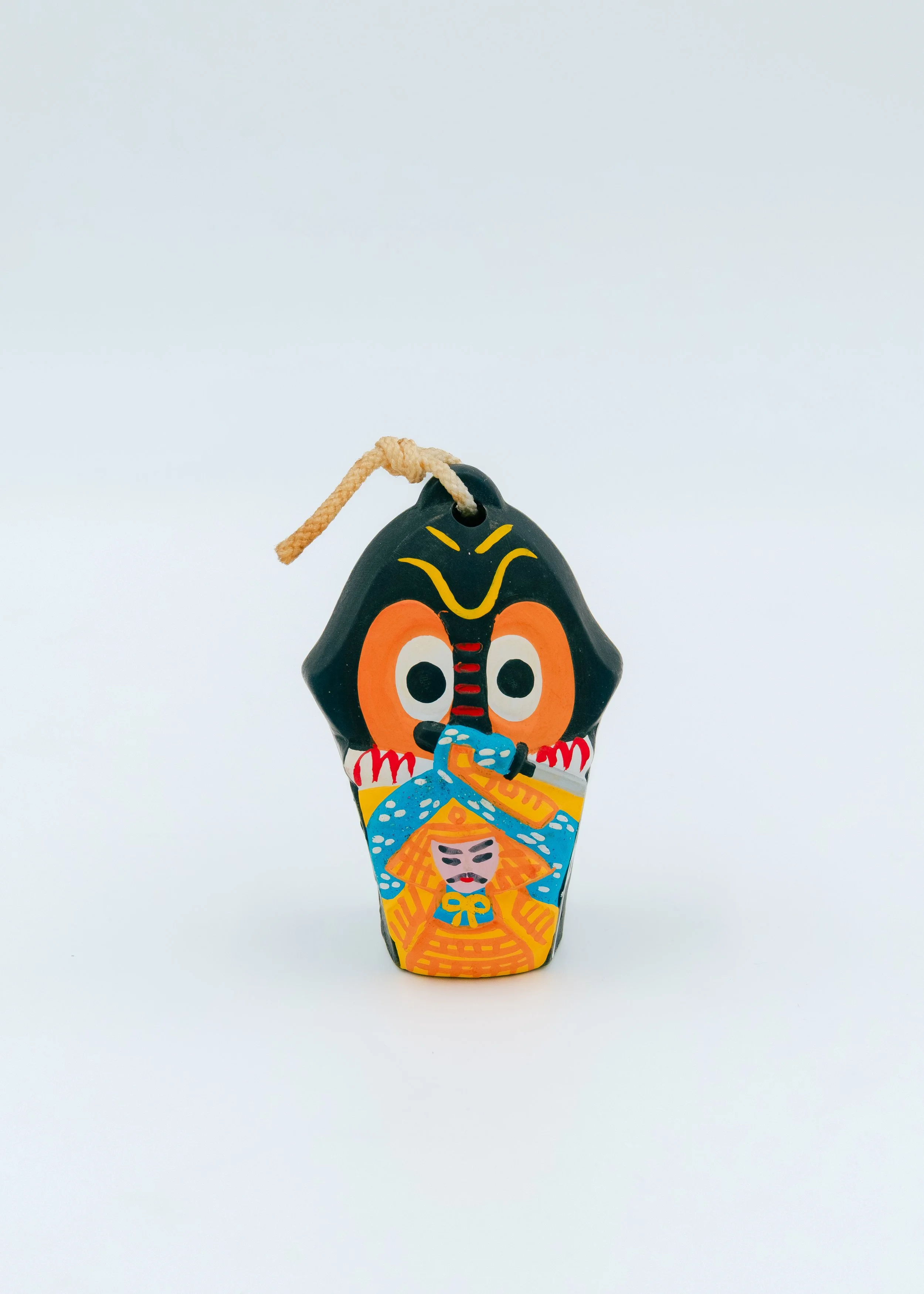 Vivid vintage Japanese pottery bell "Oni-Yocho" from Hirado, depicting the demon's assault on a samurai's helmet, painted in high-contrast pigments on an obsidian clay base.