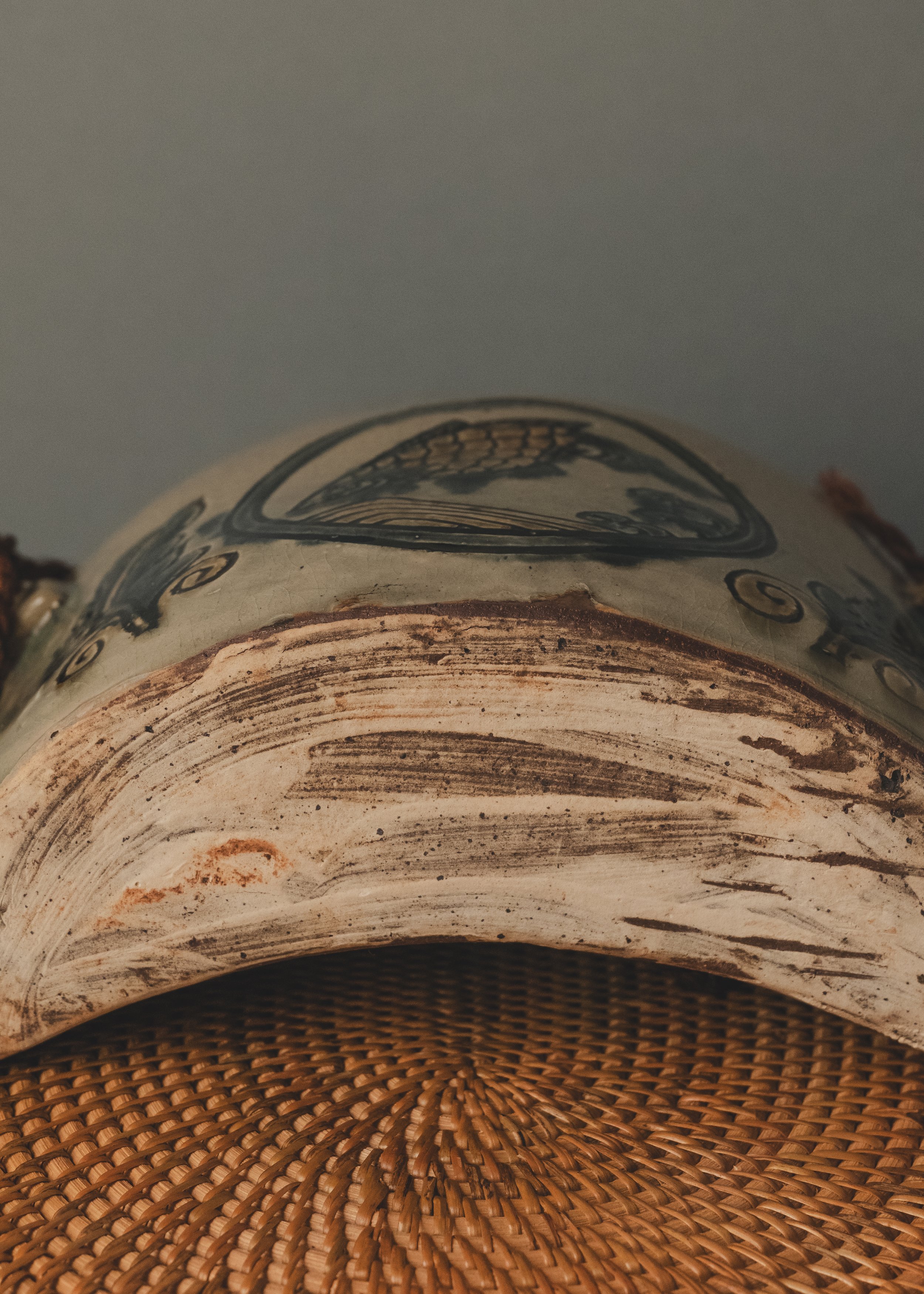 Base detail of an unglazed Tsuboya-yaki ceramic piece showing hand-painted archival marks and natural clay texture.