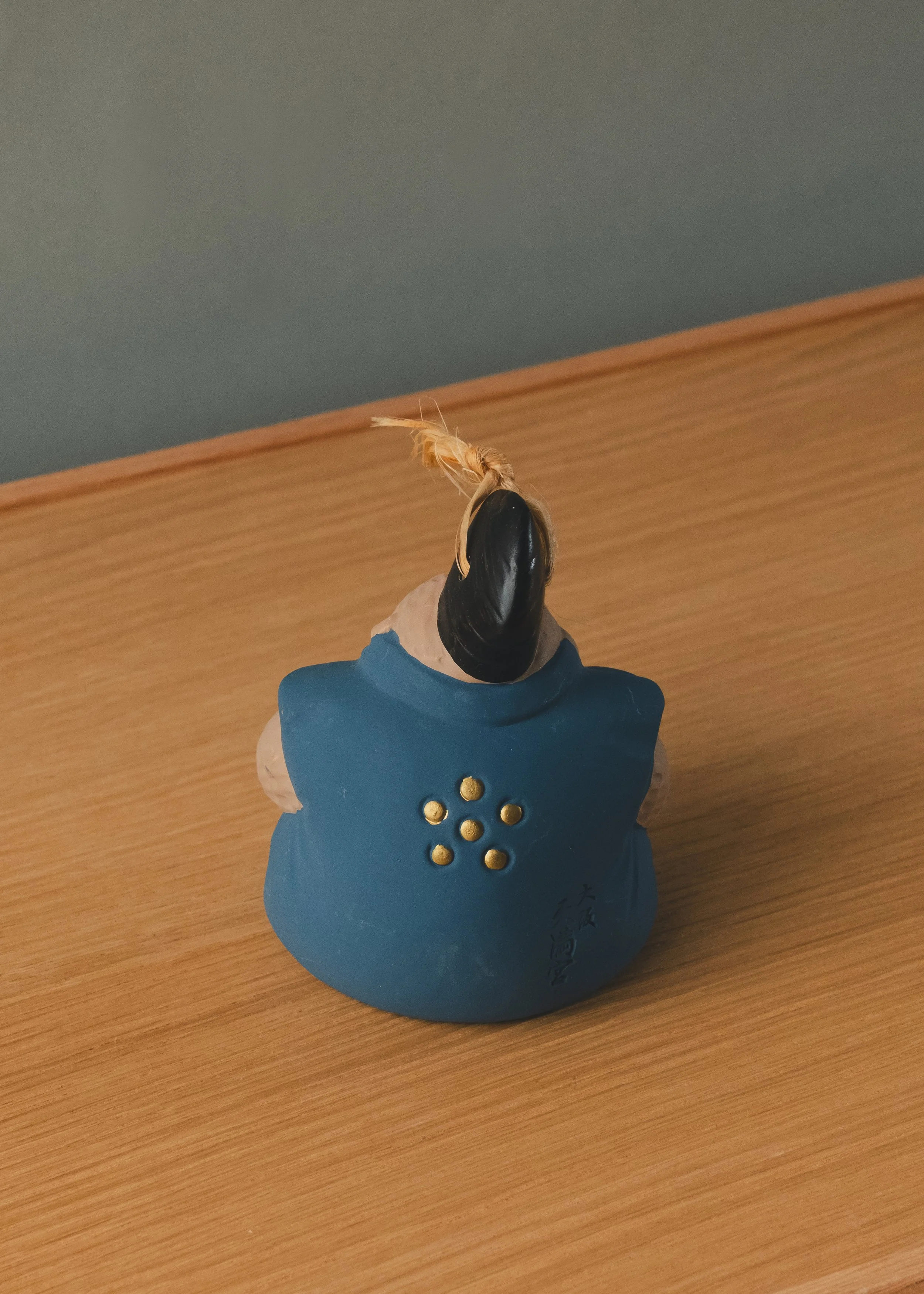 Rear view of a Japanese monkey amulet featuring the golden Ume-mon (Plum Blossom) crest of Osaka Tenmangu. An authentic specimen of Mingei folk tradition.