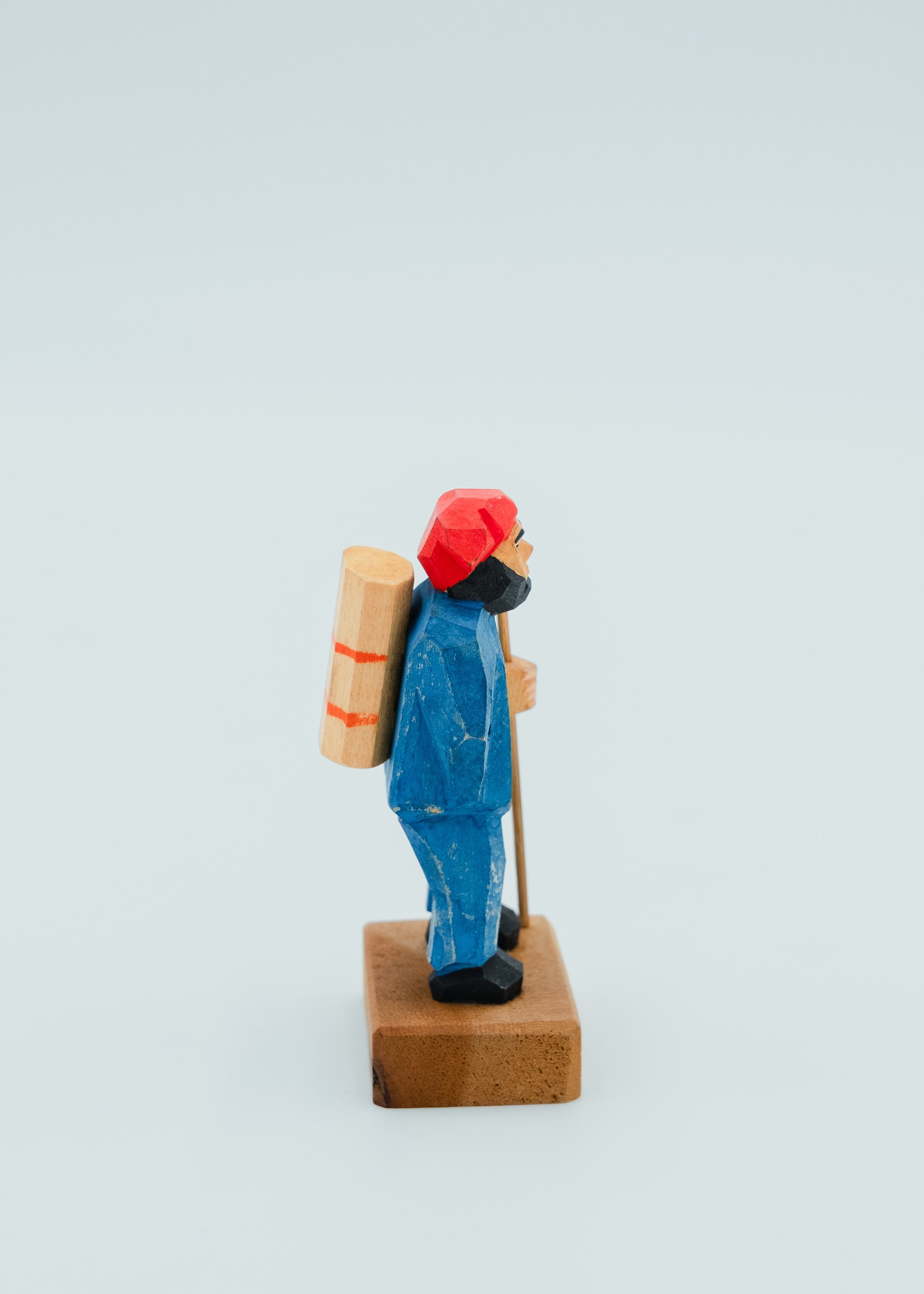 Side view of vintage Ainu wood carving doll carrying wooden backpack traveler figure Hokkaido folk art