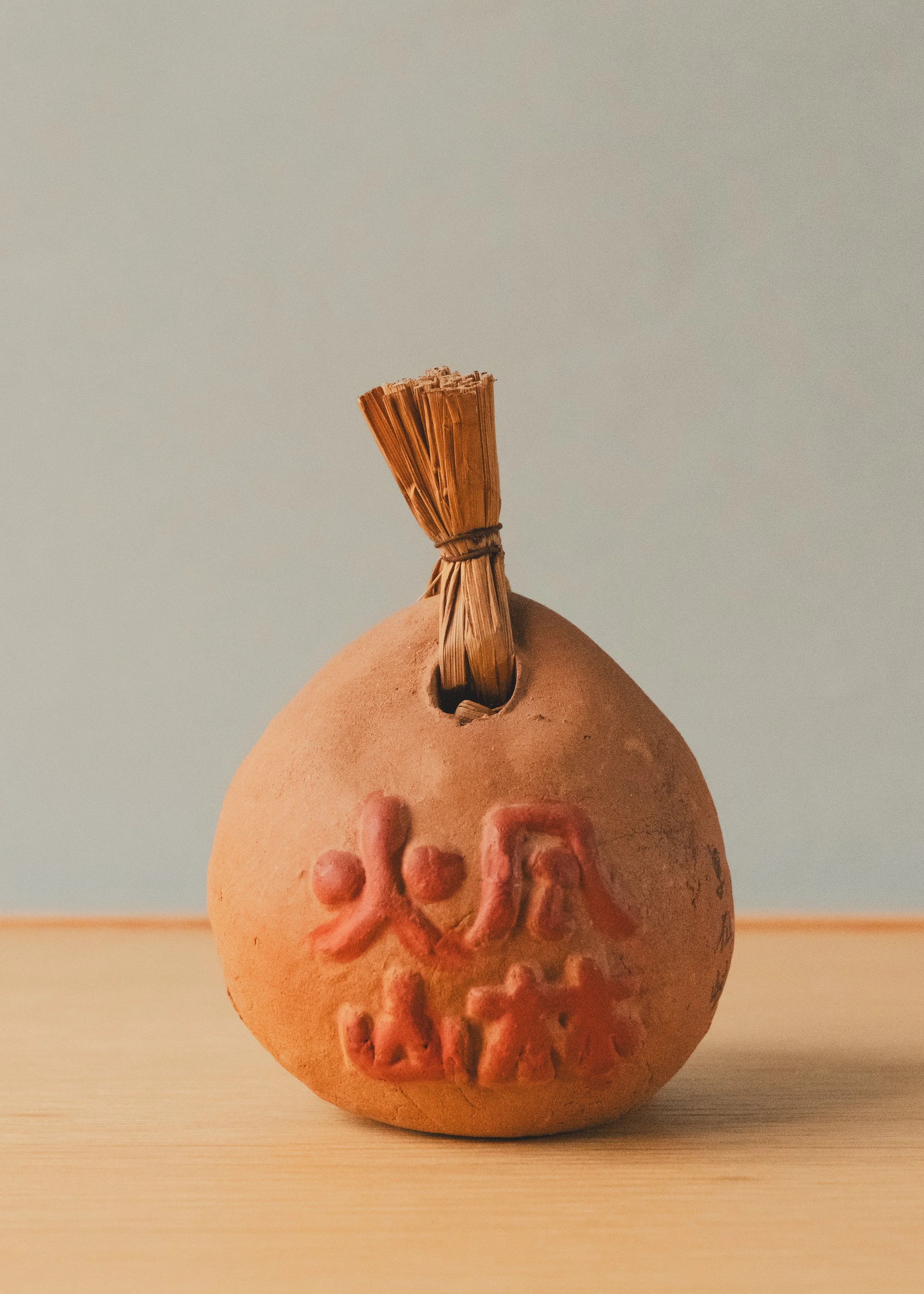 Detail of embossed vermilion "Furin-kazan" calligraphy on an unglazed Japanese clay bell, representing material honesty and spiritual utility.