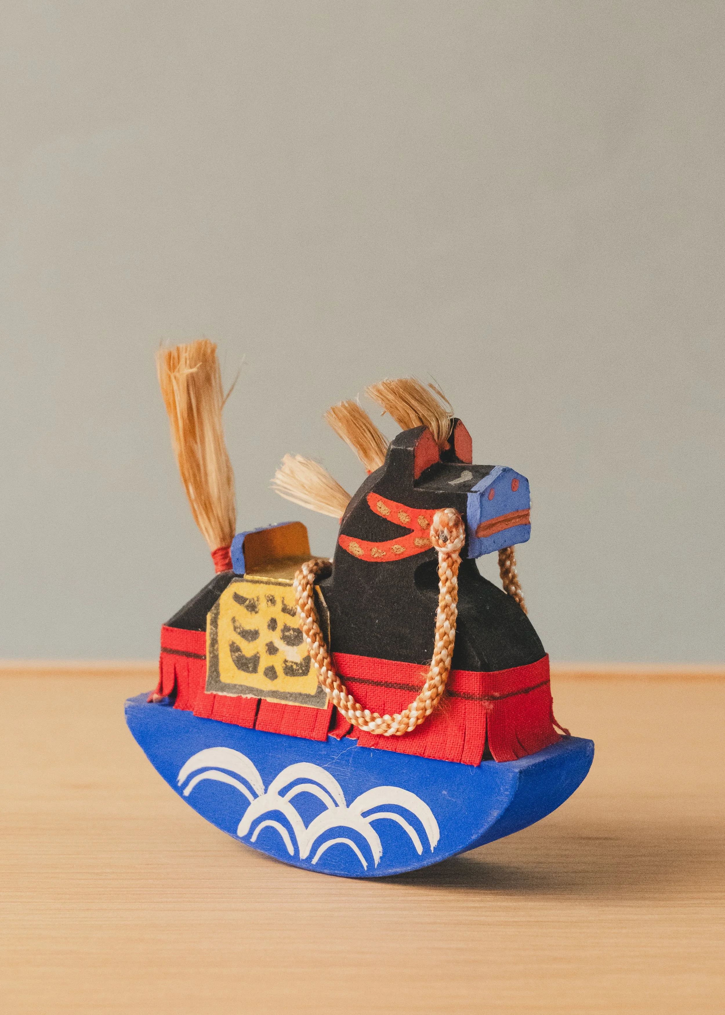 Three-quarter view of the VANGUARD STALLION 1930 sculpture, showing its minimalist black wooden body and vibrant hand-painted Japanese Mingei details.