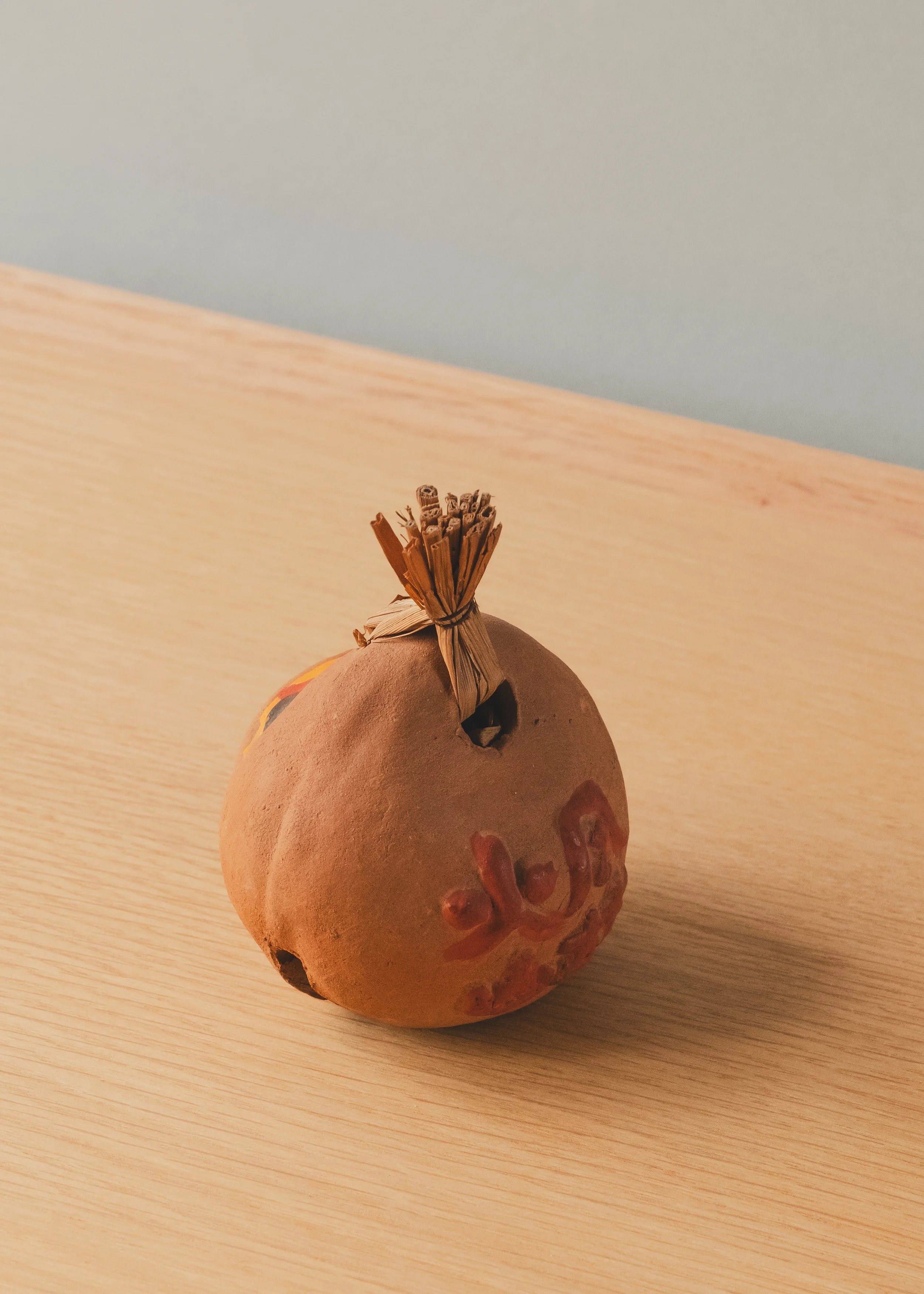 Macro shot of the unglazed clay finish on a Shinto ritual bell, highlighting the organic "Patina of Survival" and 1-of-1 hand-painted details.