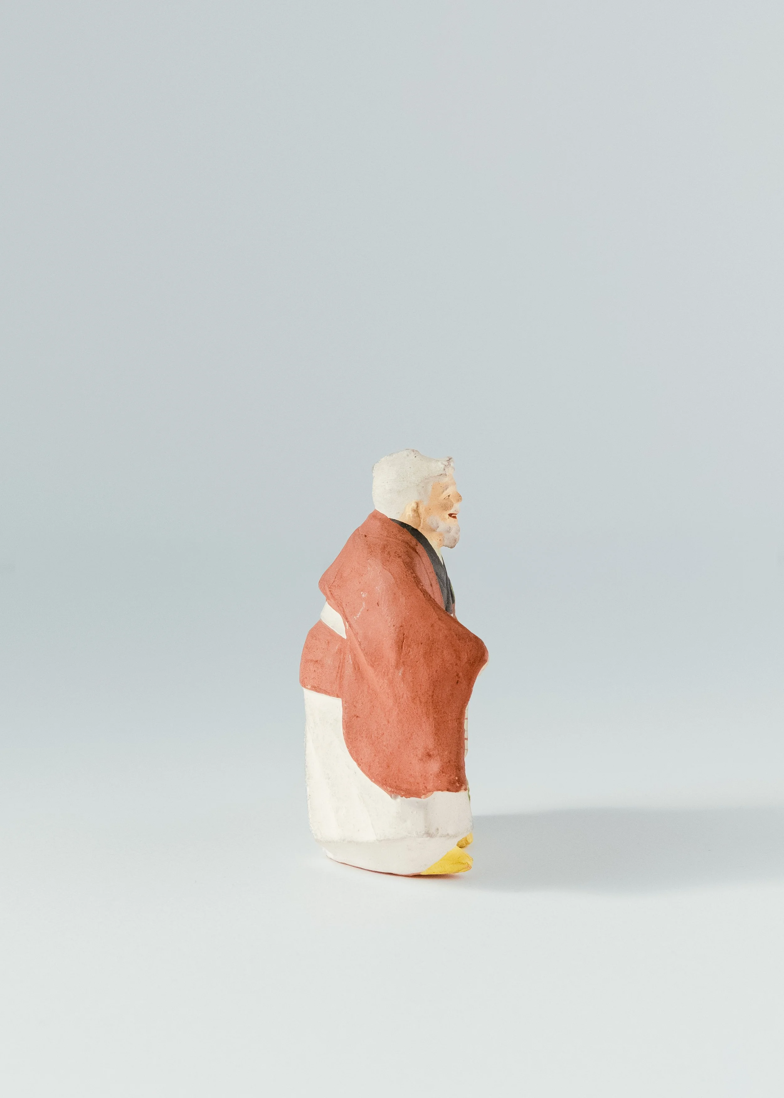 Side profile of Japanese clay god Jurōjin figurine folk pottery long life symbol monk with scroll