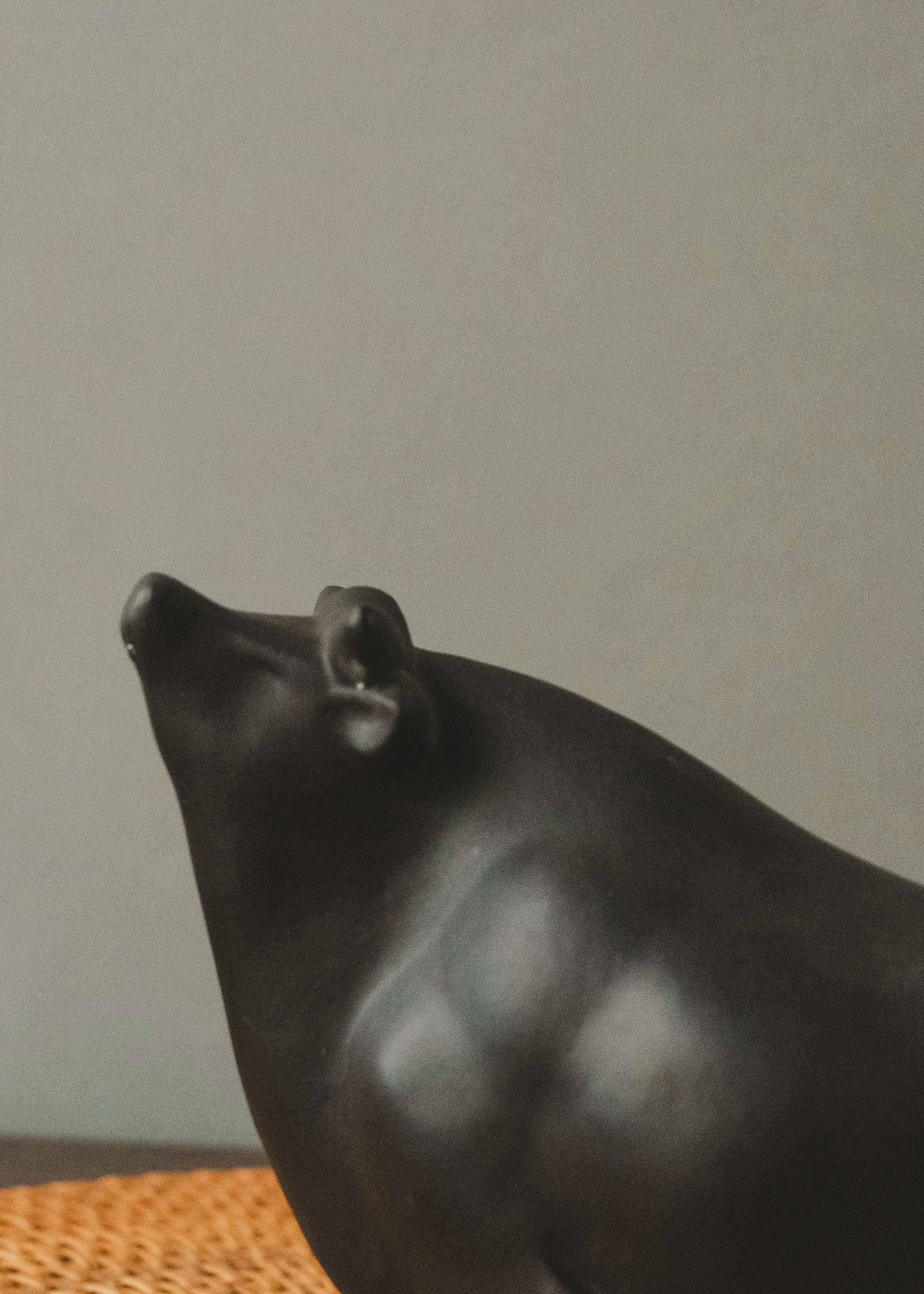 Close-up of the abstract, featureless face of a vintage Japanese bull talisman. Emphasizing the meditative presence and minimalist clay-firing craftsmanship.