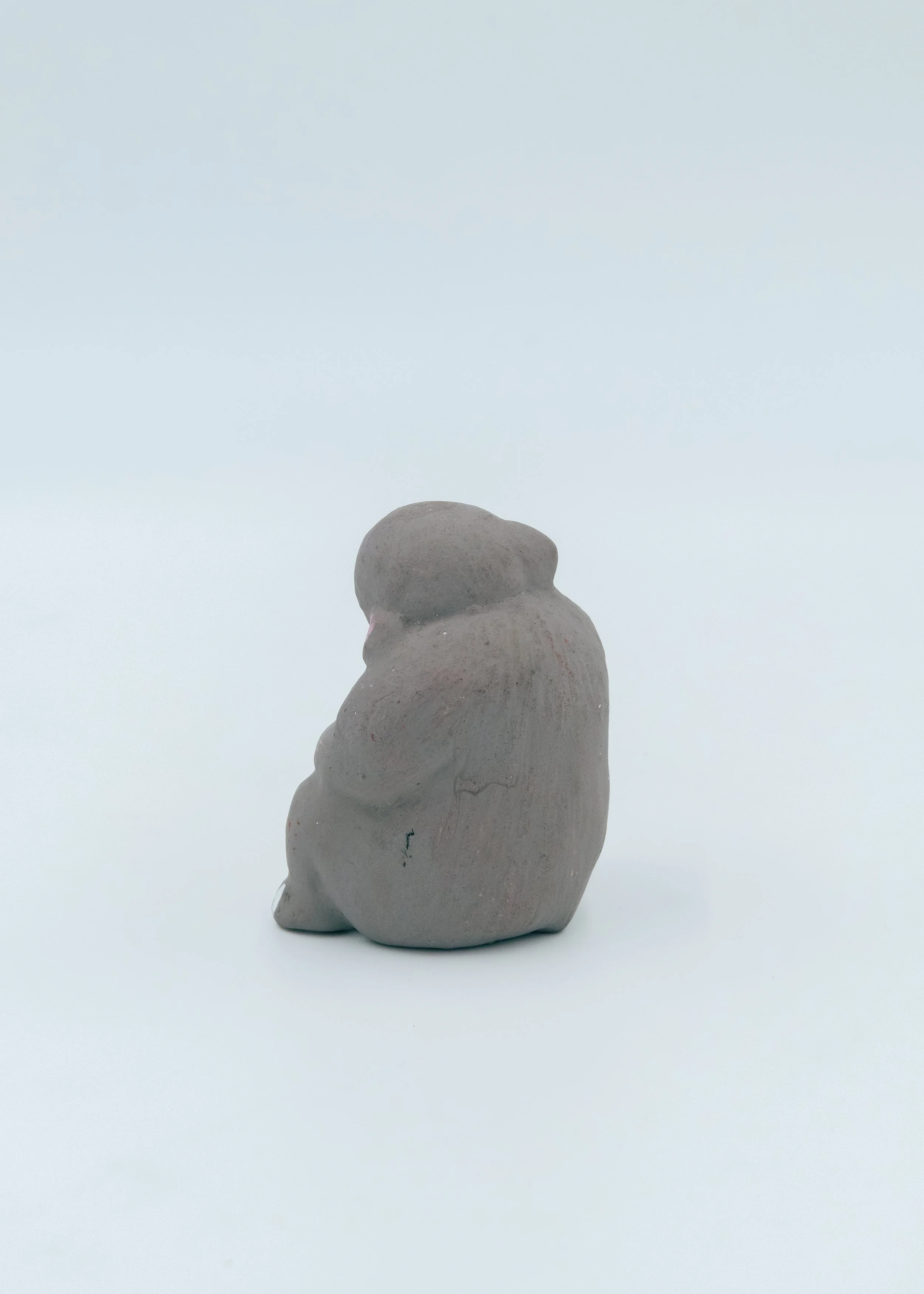 Reverse side of an anonymous Showa-era clay monkey ornament, showcasing the rustic matte grey earthen texture and artisan-formed curves.