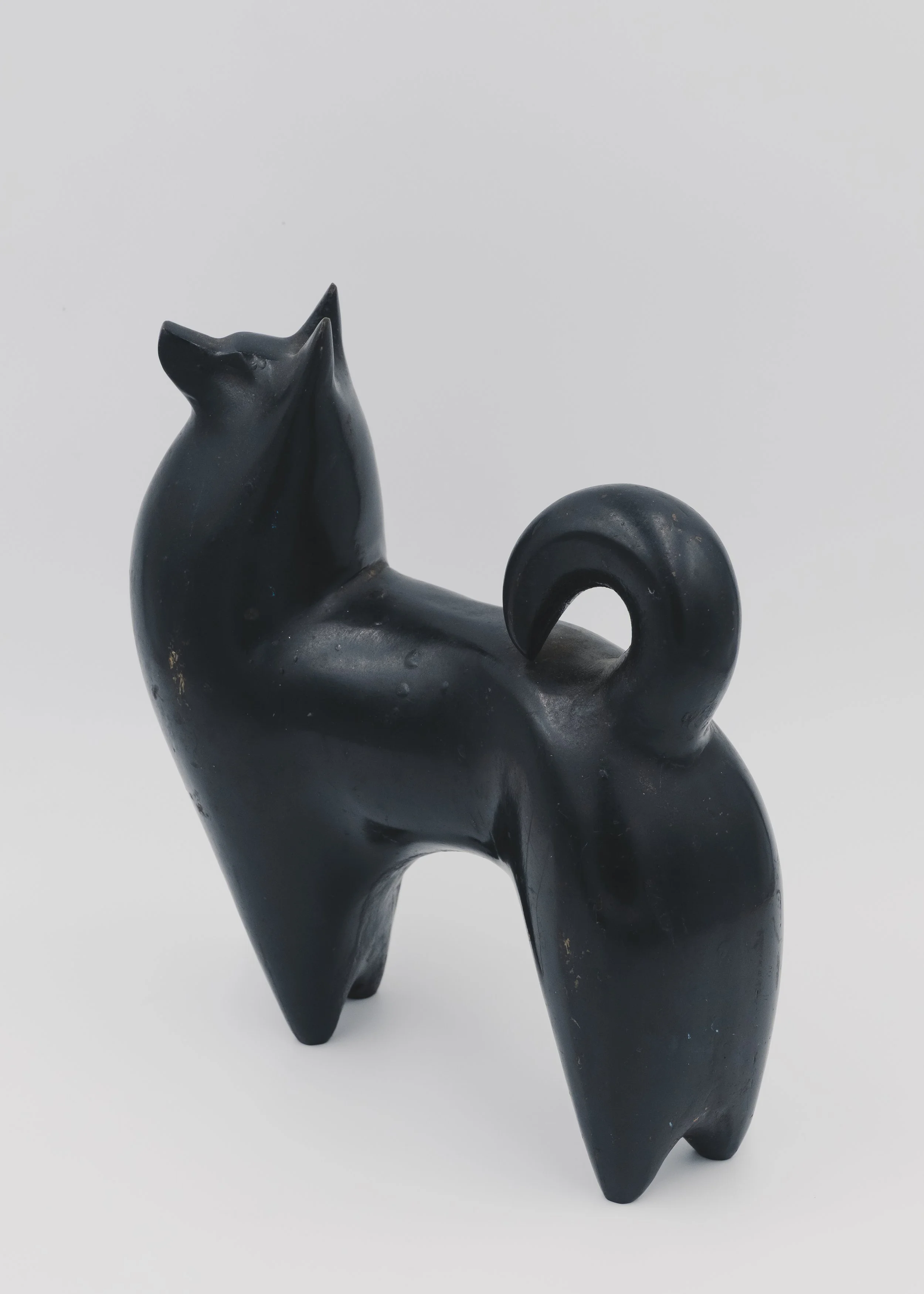 Side view of a vintage Nambu Tekki cast iron dog sculpture with a traditional curled tail (Maki-o) and nocturnal black finish, Japandi style decor.