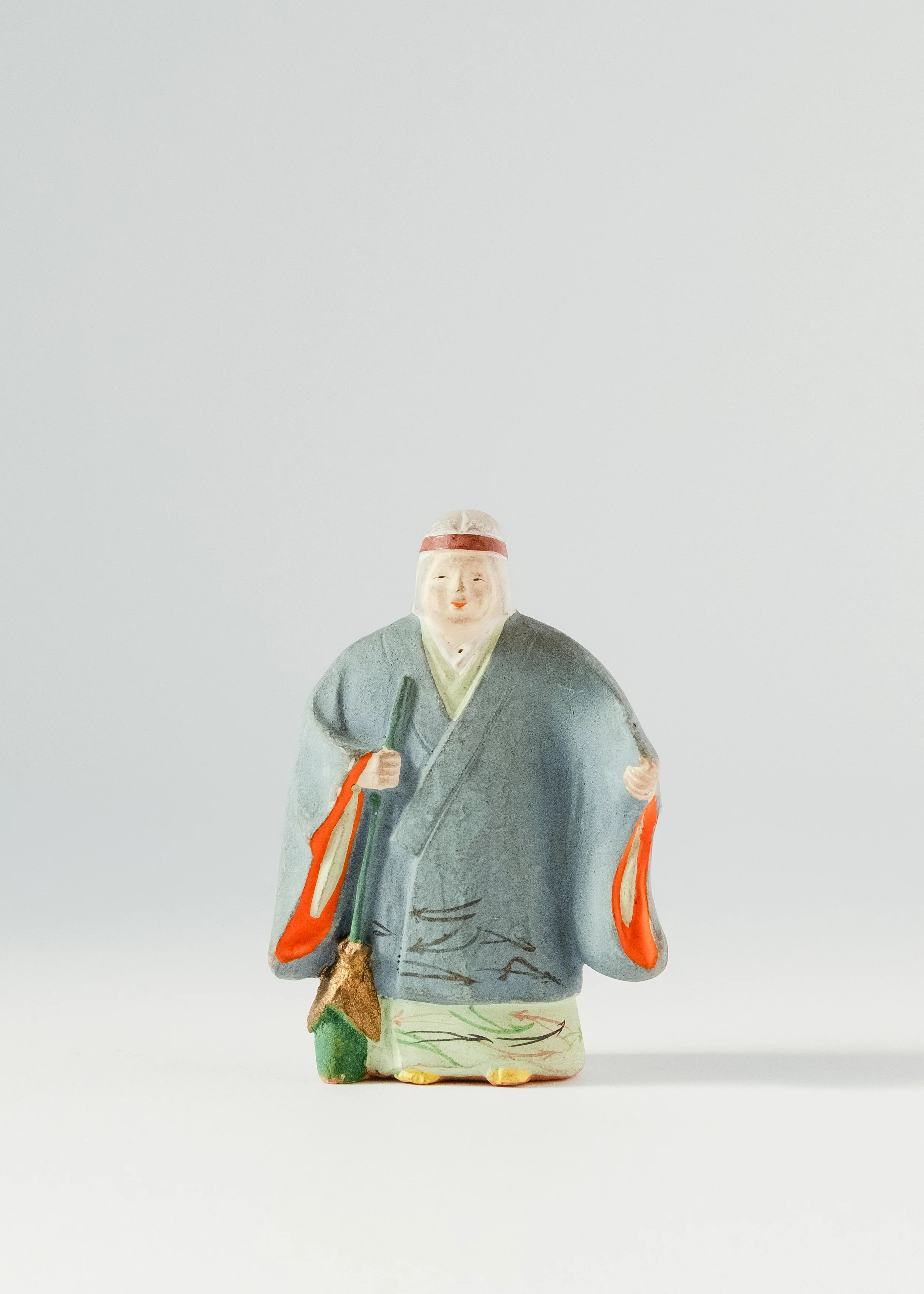 Front view of smiling old man clay doll holding broom Takasago legend symbol of happy marriage