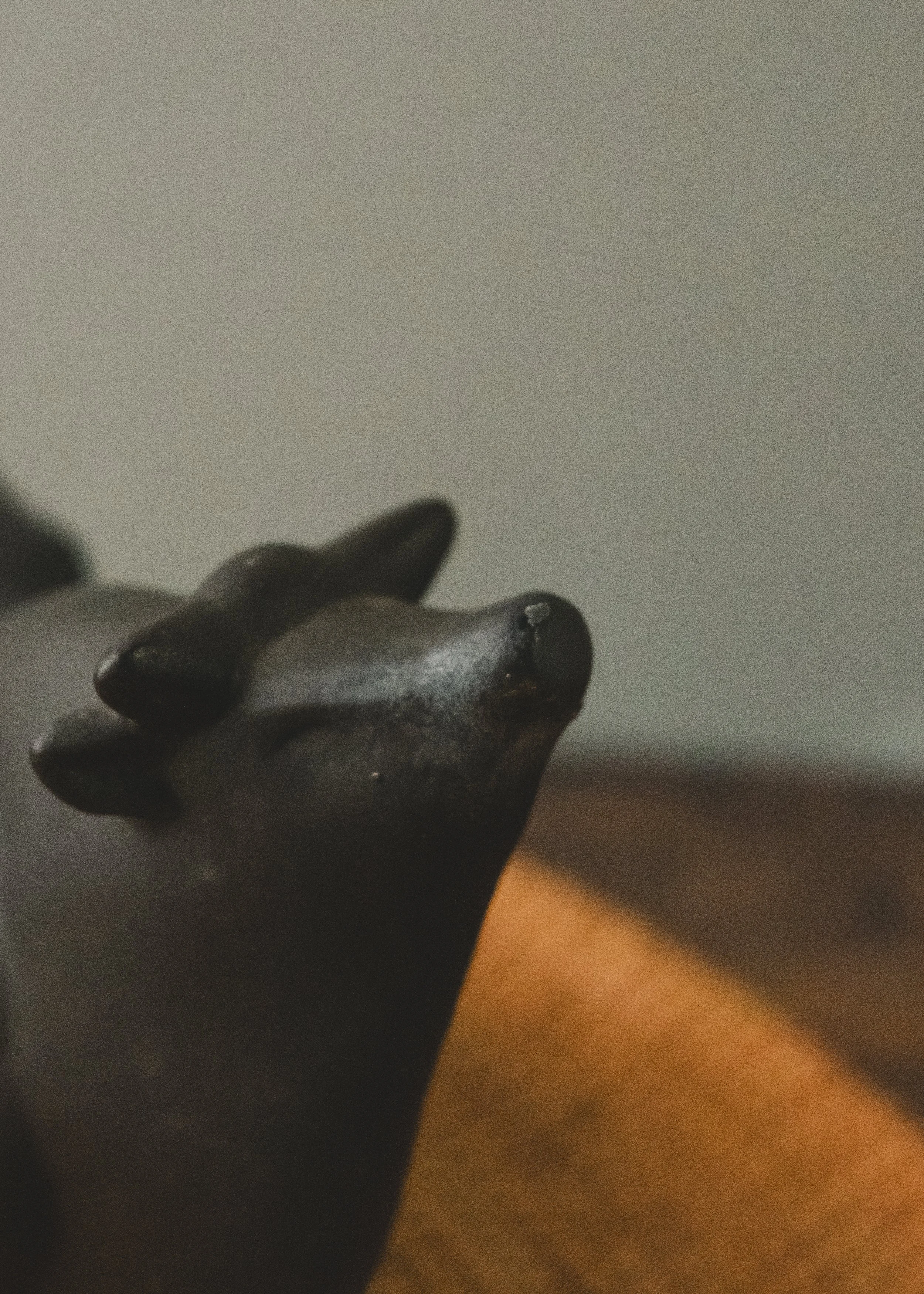 Close-up of the abstract, featureless face of a vintage Japanese bull talisman. Emphasizing the meditative presence and minimalist clay-firing craftsmanship.