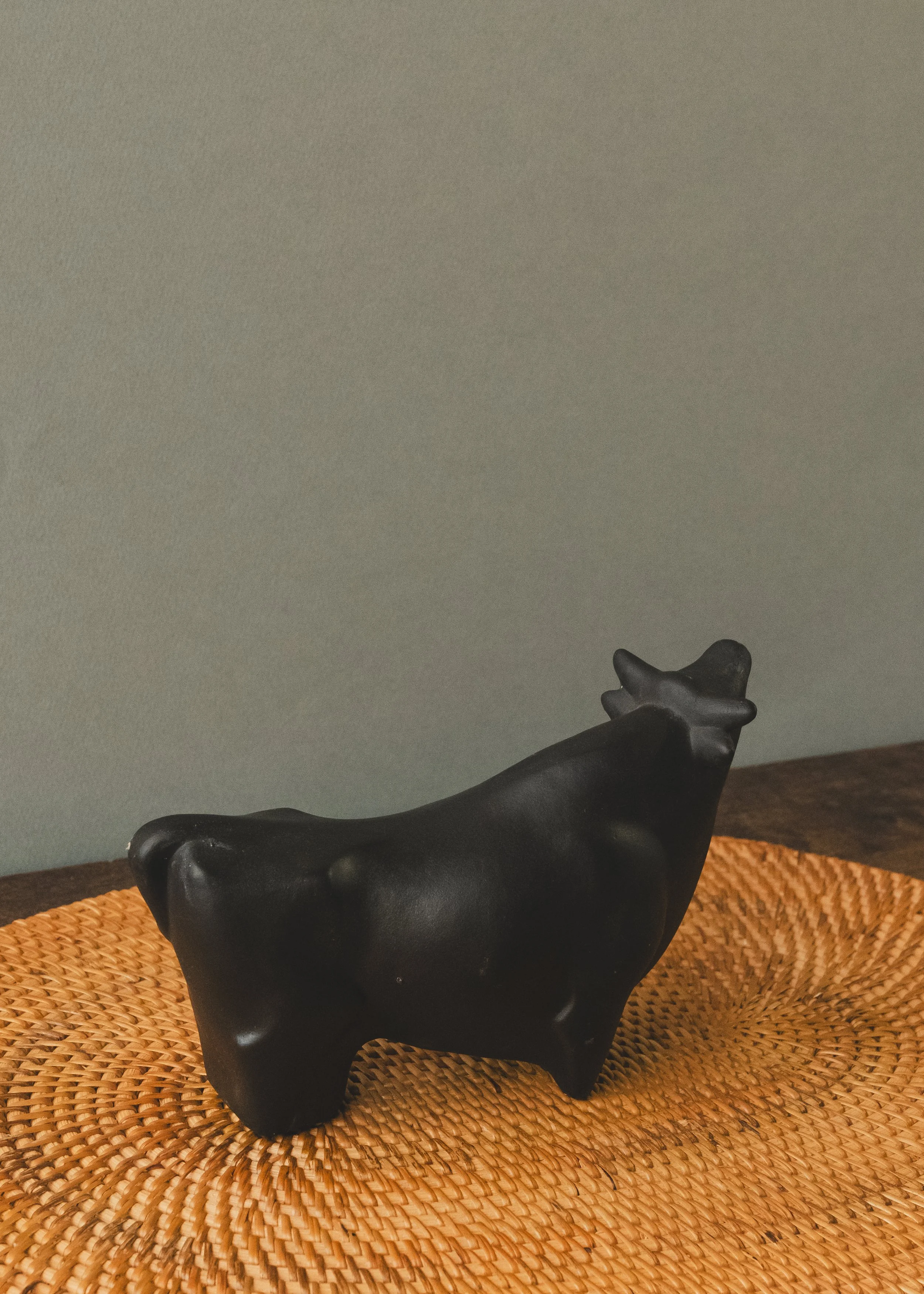 Side profile of an anonymous Japanese black bull figurine. A mid-century minimalist decor piece featuring deep, light-absorbing matte glaze and a grounded, authoritative stance.