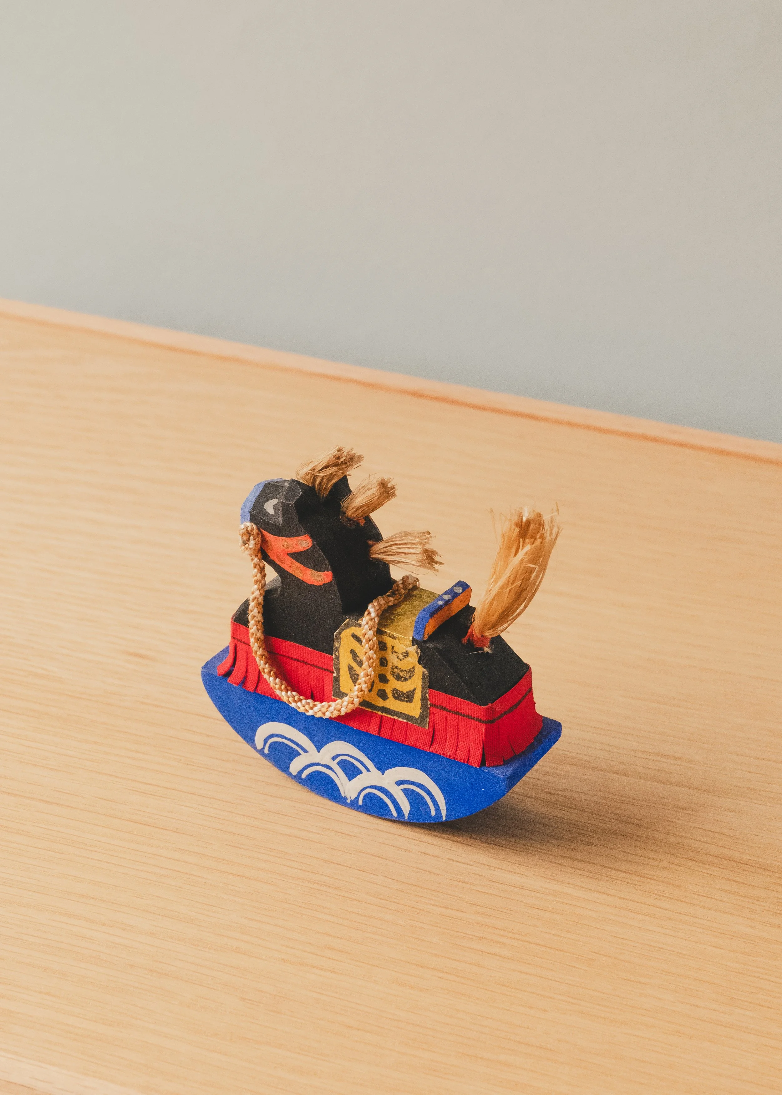 Rear perspective of THE VANGUARD STALLION 1930, a hand-carved vintage Japanese Paulownia wood horse with natural straw tail and a blue rocking pedestal.