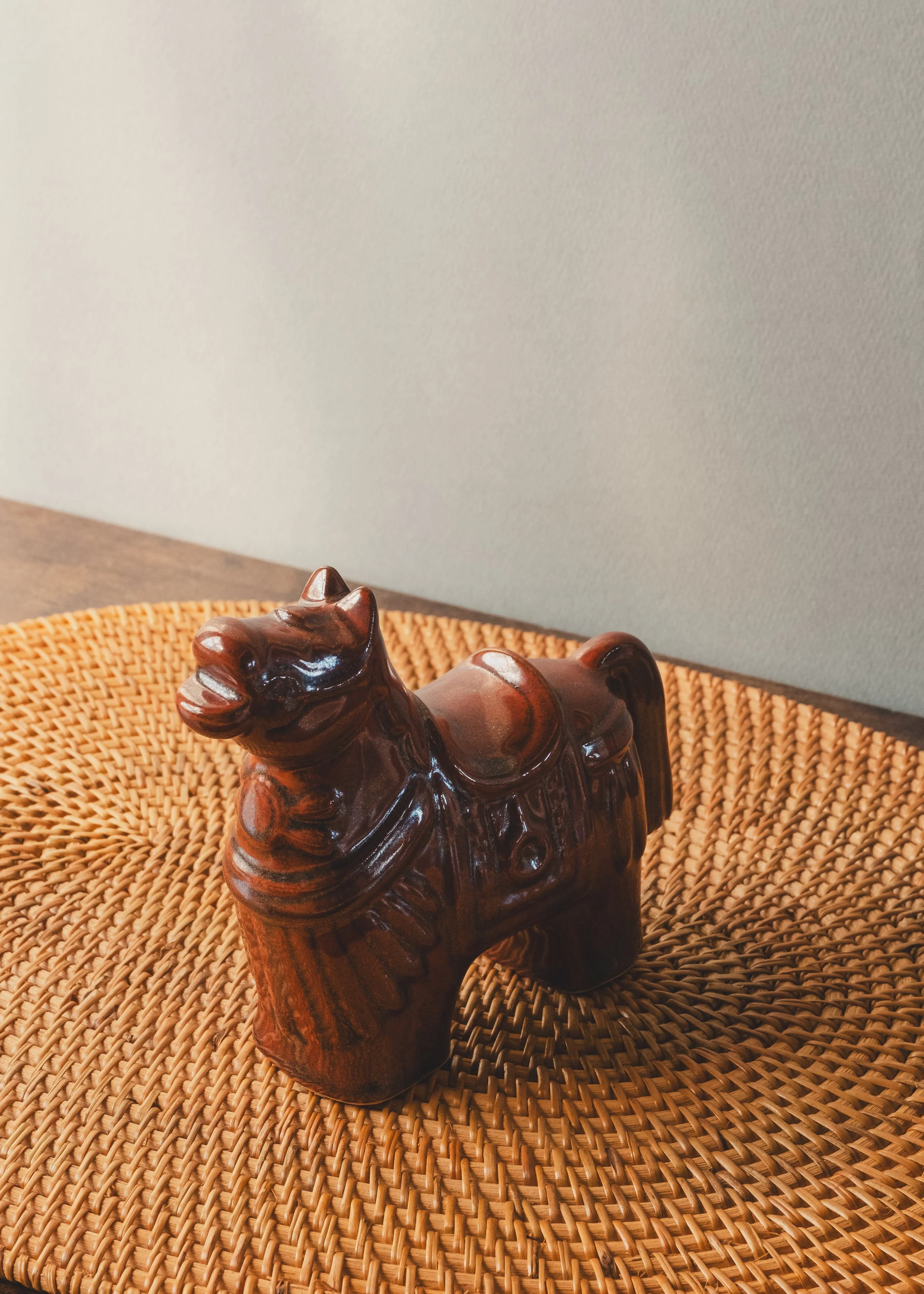 Hand-painted brown glazed pottery horse with traditional saddle relief design.
