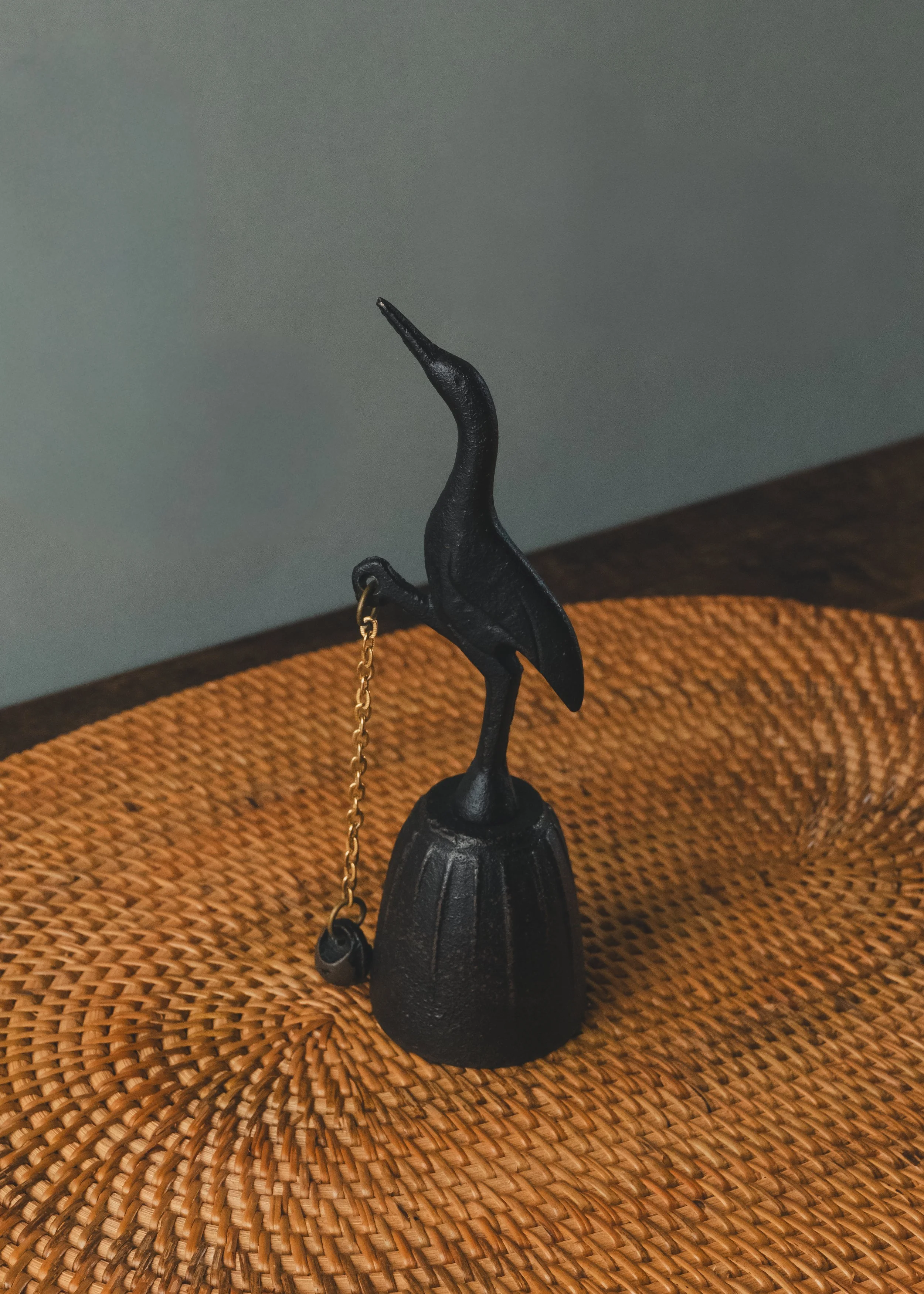 Kinetic table bell (Taku-Rin) featuring a Nambu Tekki iron crane. View showing the external clapper system and brass chain. A Showa-era artifact from Iwate, Japan.