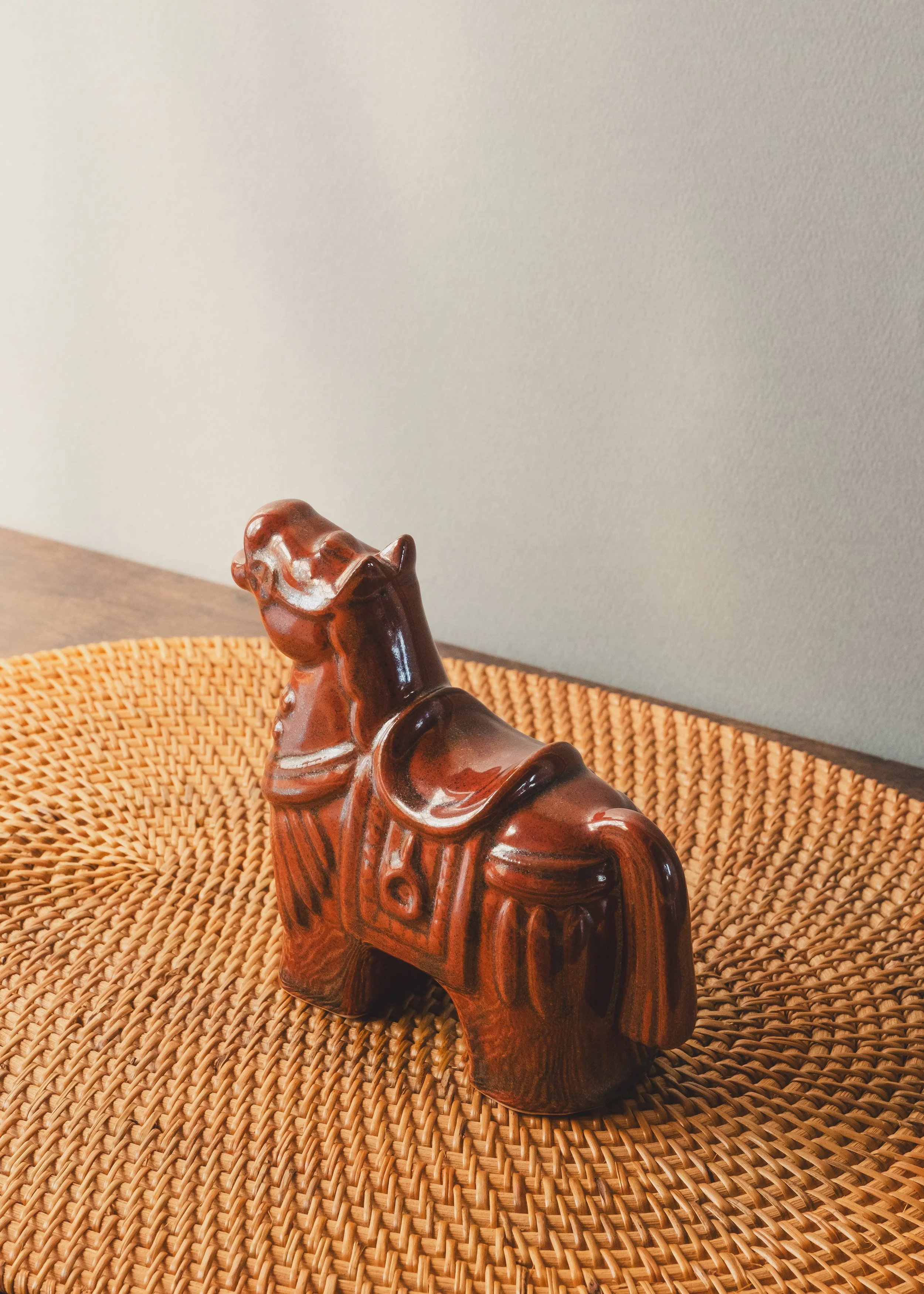 Hand-painted brown glazed pottery horse with traditional saddle relief design.