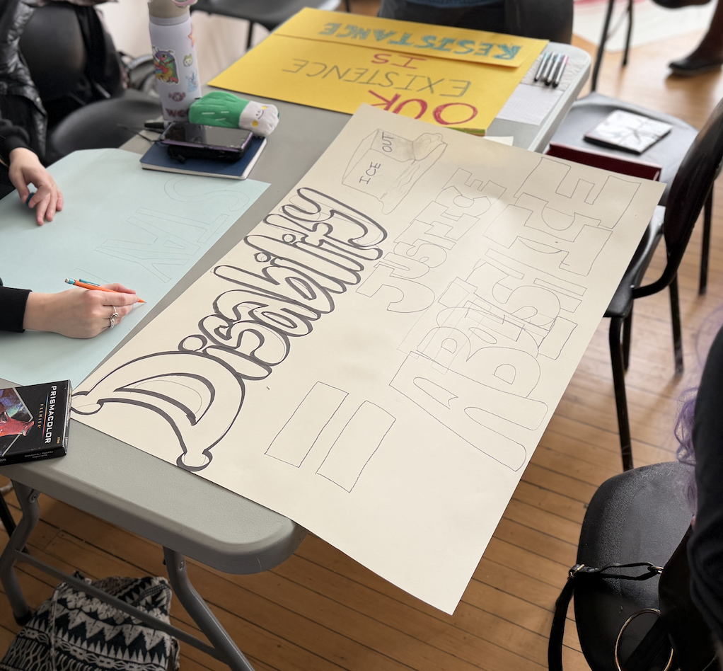 A group of people with posters and banners on a table at a meeting or event.