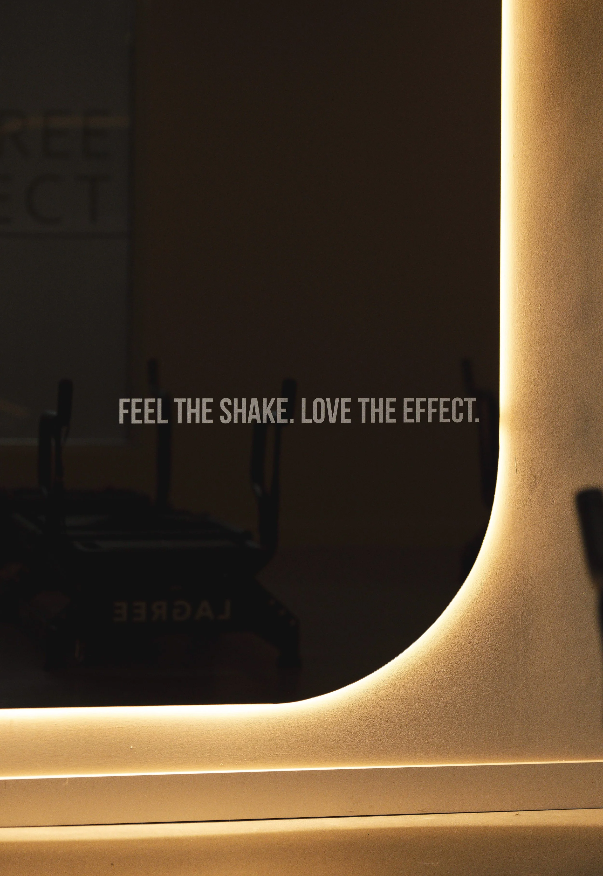 A mirror with warm lighting and the text 'Feel the shake. Love the effect.' displayed on it.