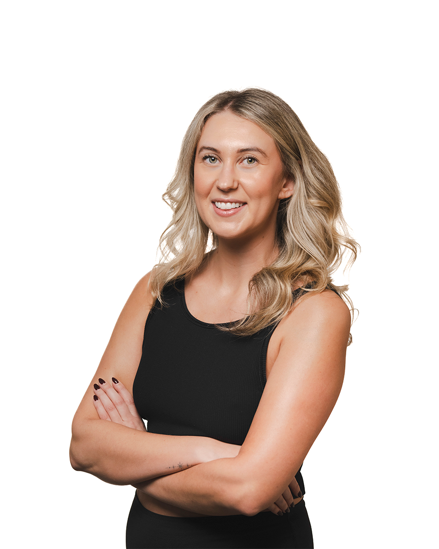 A woman with blonde, wavy hair smiling and crossing her arms, wearing a black sleeveless top against a white background.