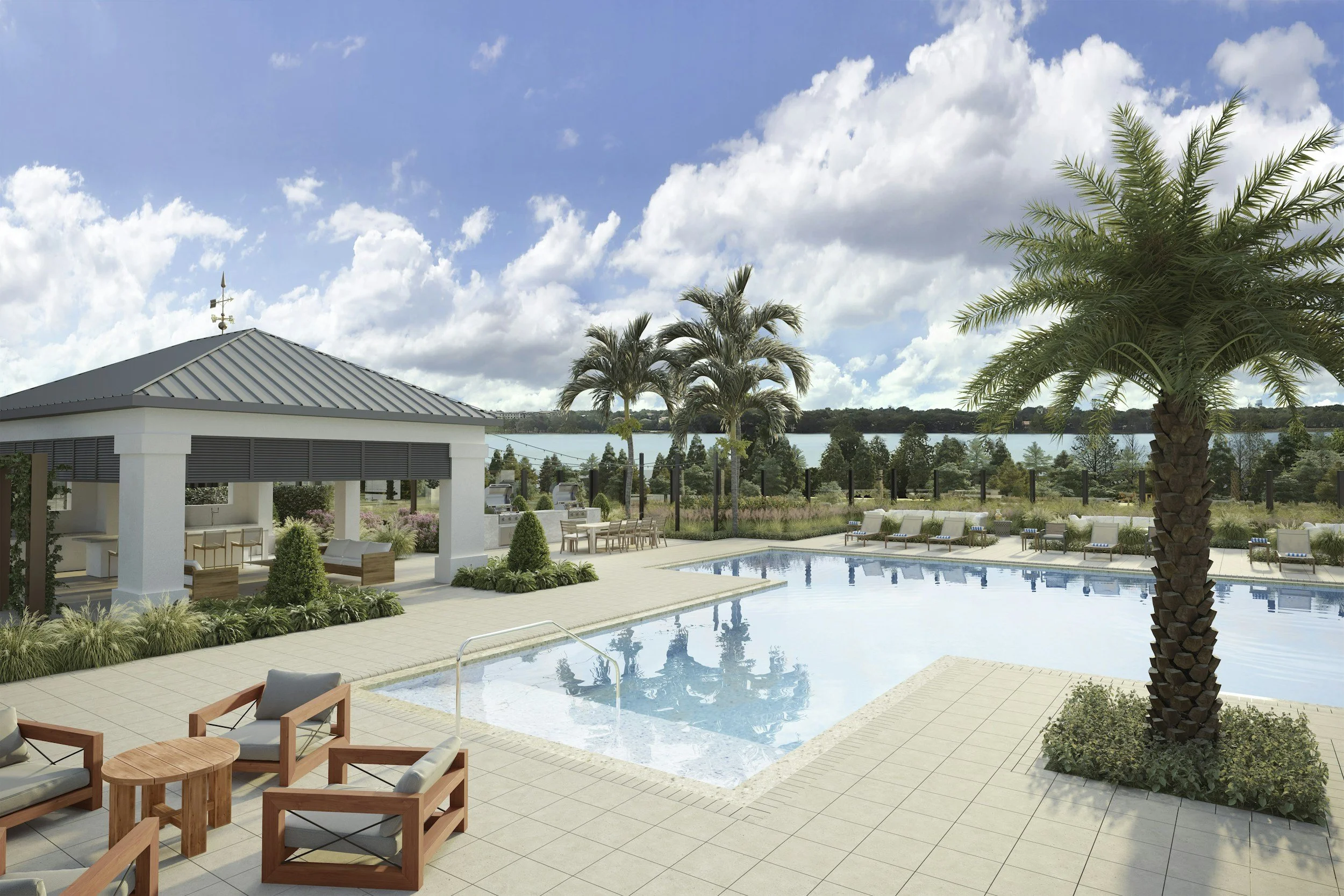 A luxurious outdoor pool area with modern furniture, palm trees, and a scenic lake view under a partly cloudy sky.