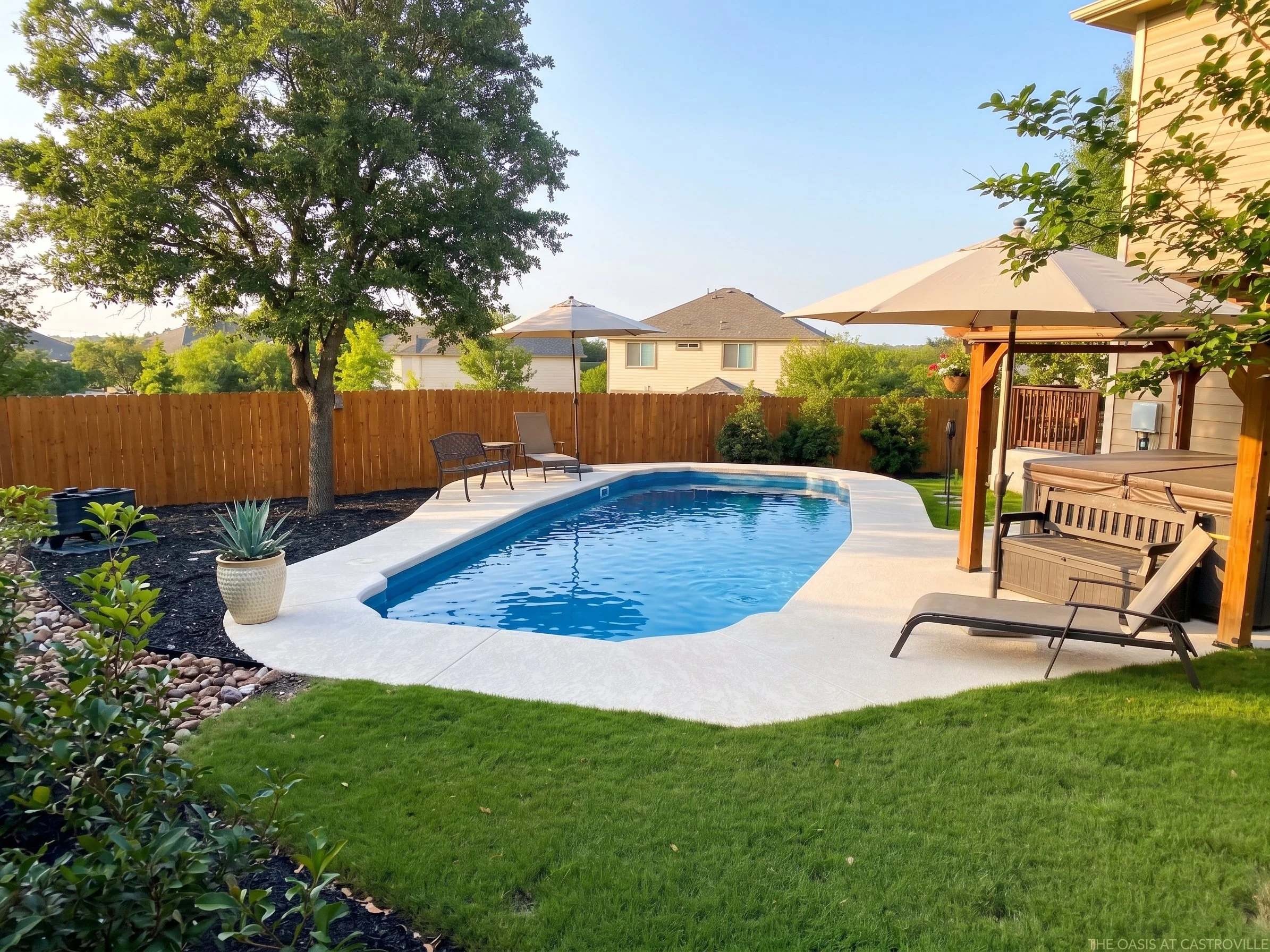 Backyard with a swimming pool, patio furniture with umbrellas, a small lawn, and a wooden fence.