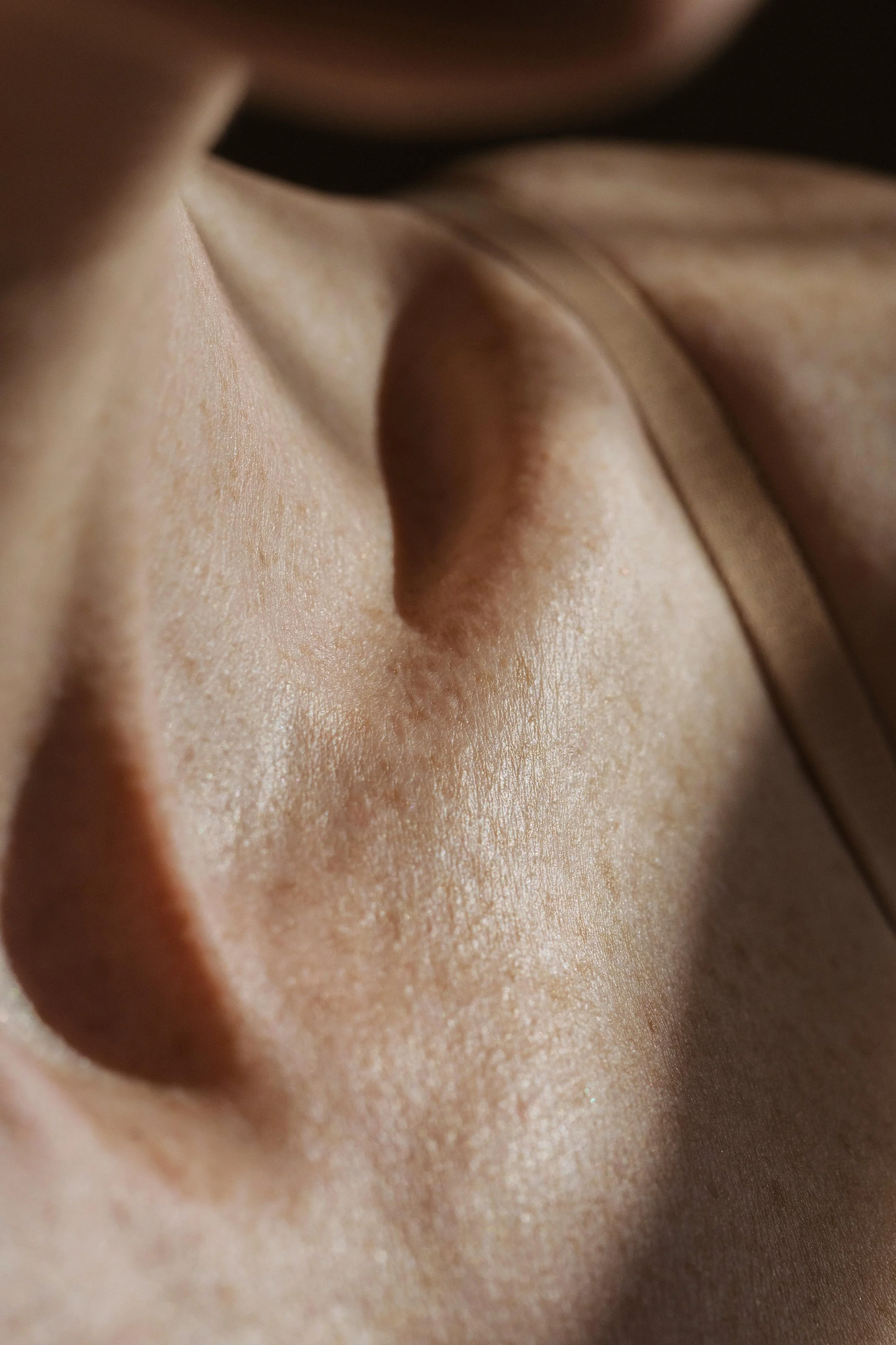 Close-up of a person's navel and surrounding skin, with soft lighting and a neutral background.