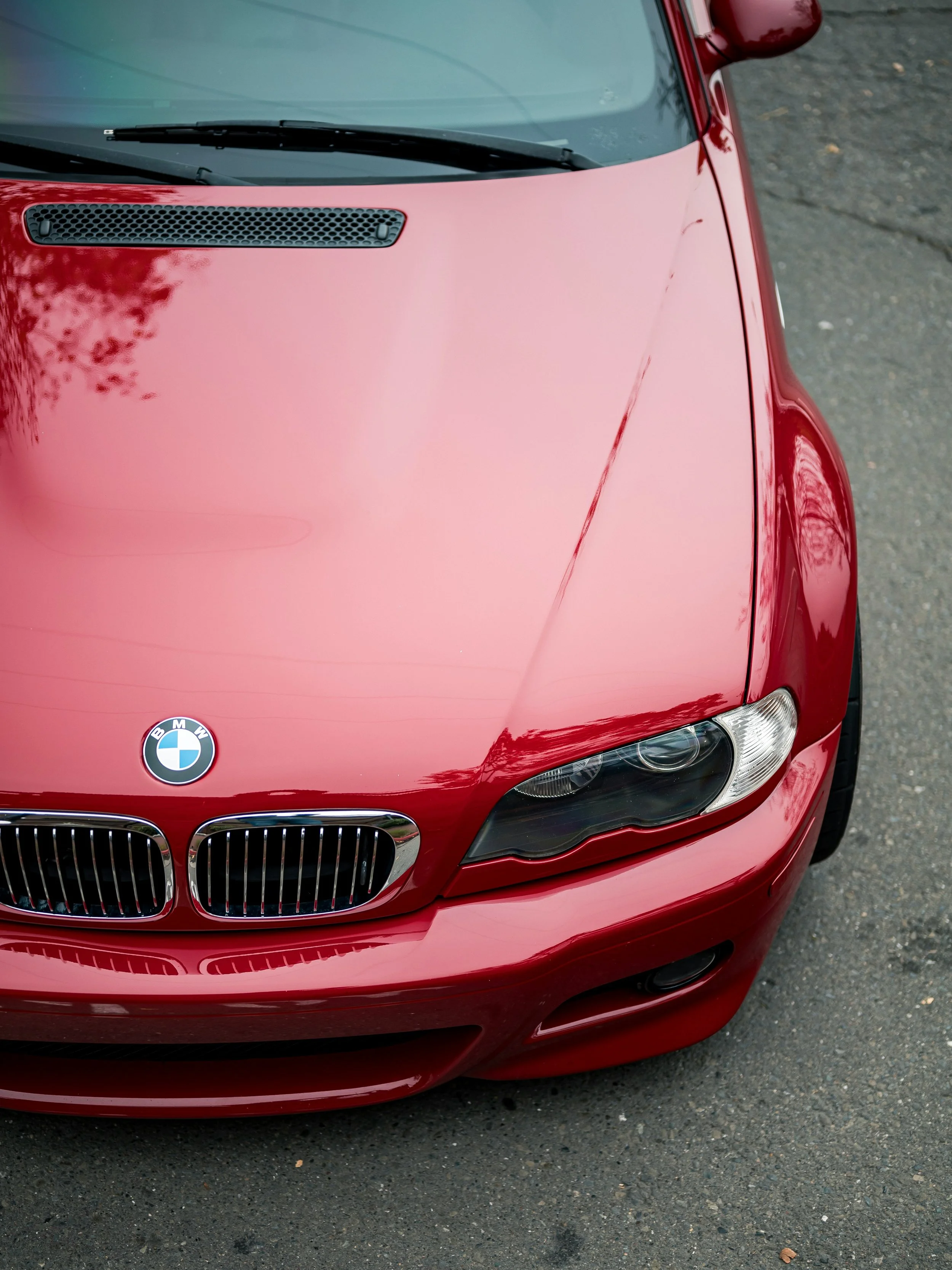 Red BMW car, front view, on asphalt road.