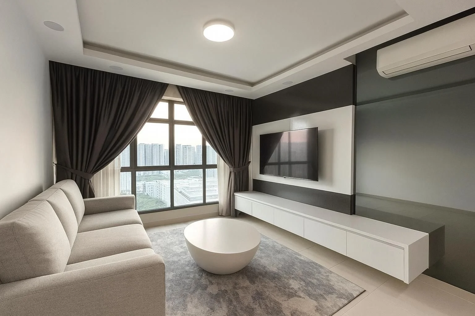Modern living room with beige sofa, white coffee table, gray area rug, wall-mounted flat-screen TV, large window with dark curtains, and cityscape view