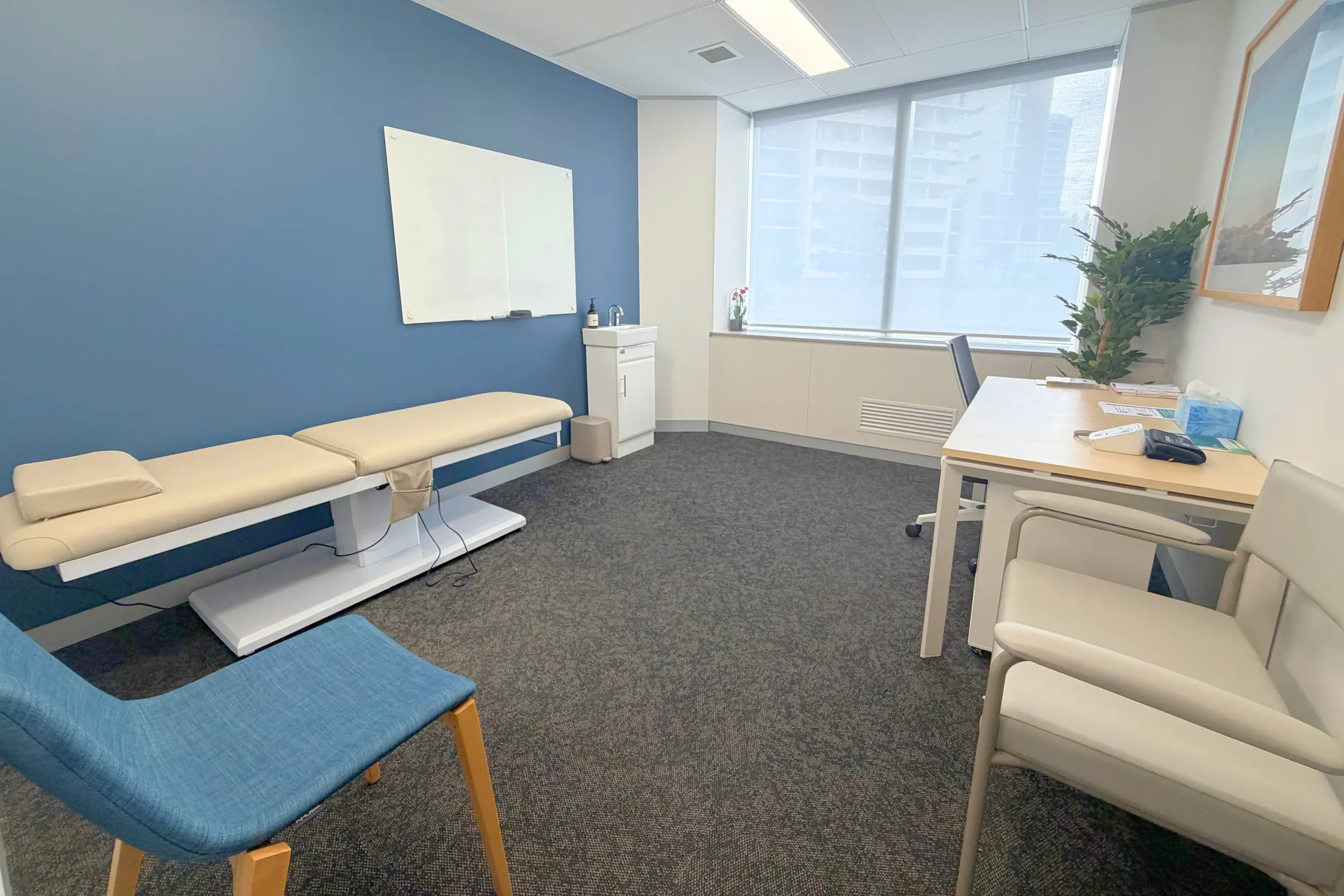 Consultation room at Naia Health osteoarthritis clinic in St Leonards Sydney with examination bed, patient seating, desk and natural light window
