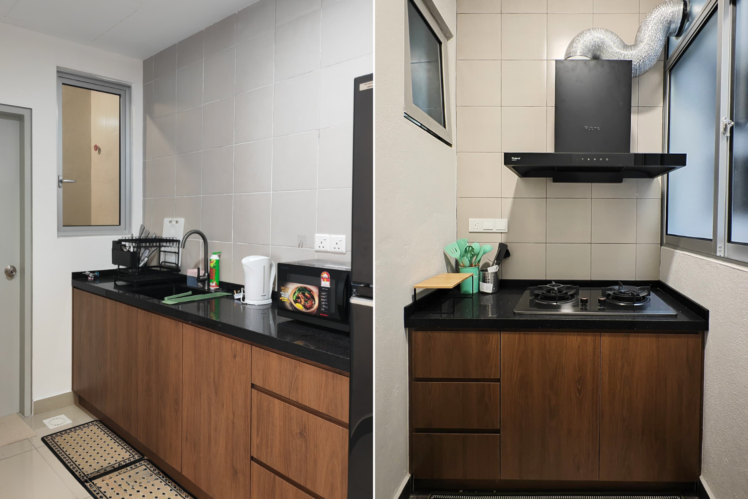 View of a small kitchen with beige tiled walls, a window, a black countertop, wooden cabinets, and various appliances including a microwave, kettle, and dish drying rack.