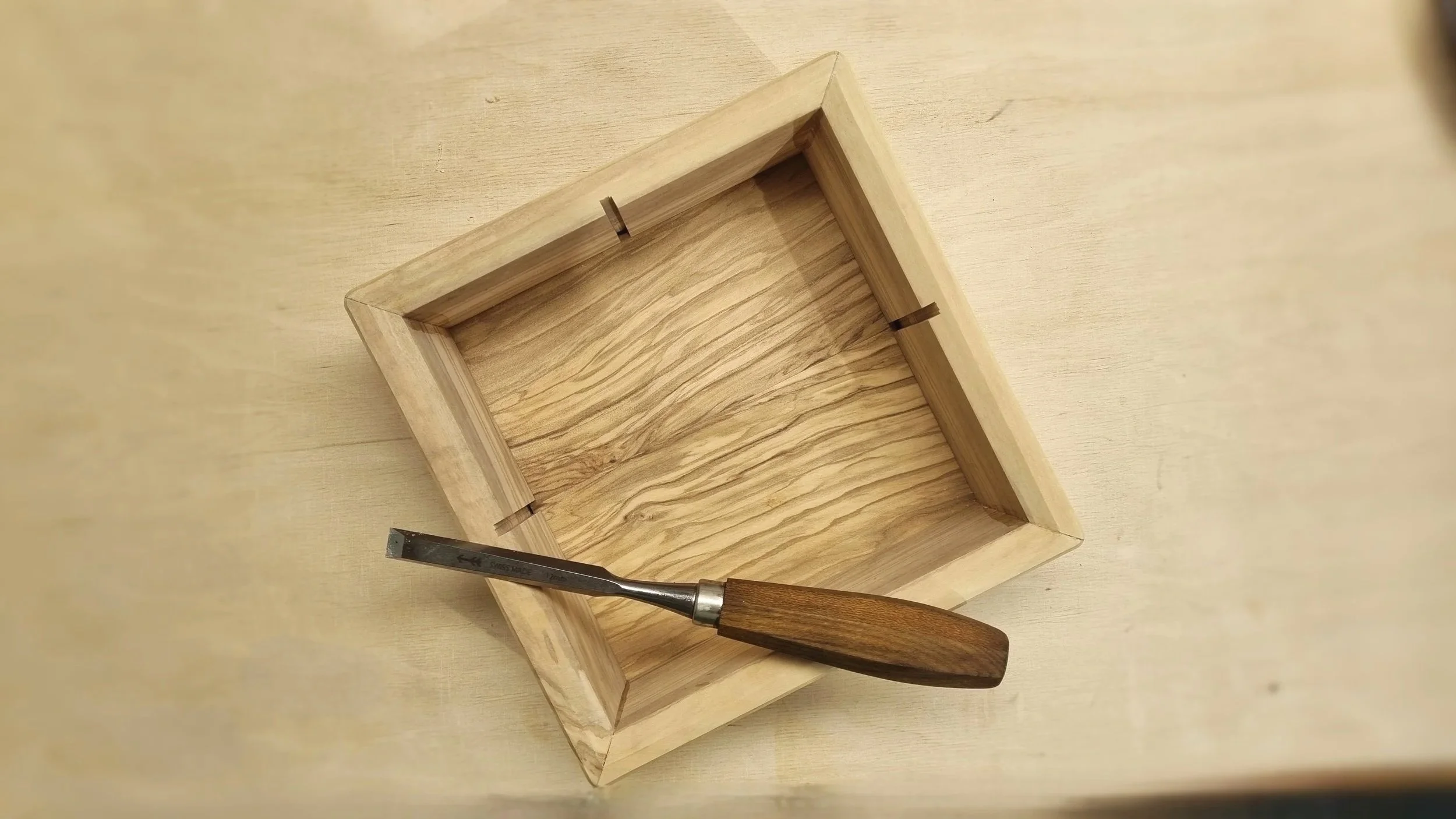 Olivenholzkiste auf Holzbrett.