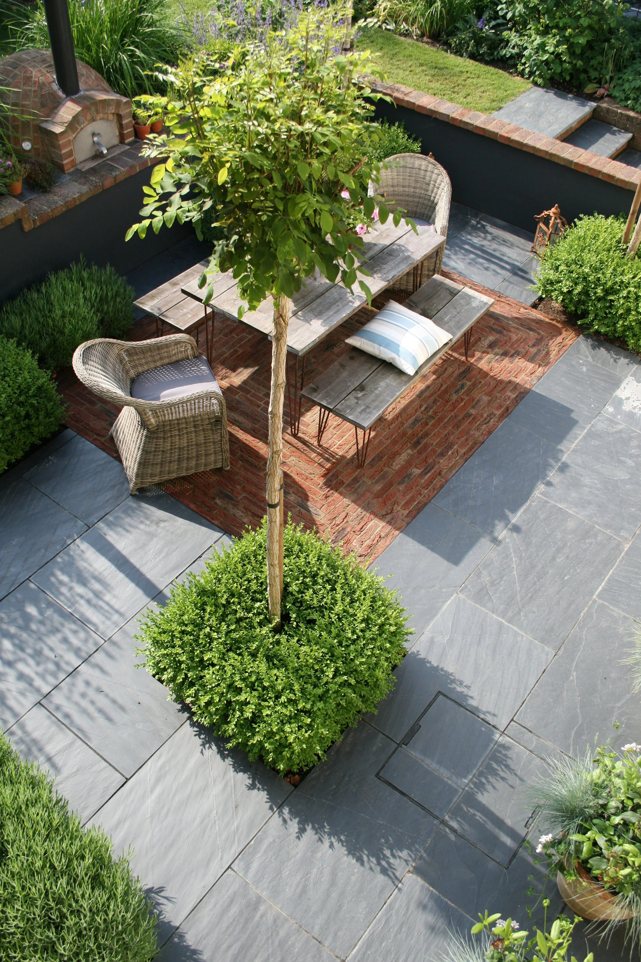 Contemporary courtyard garden with brick Pizza oven, dining terrace, slate paving and central tree planting