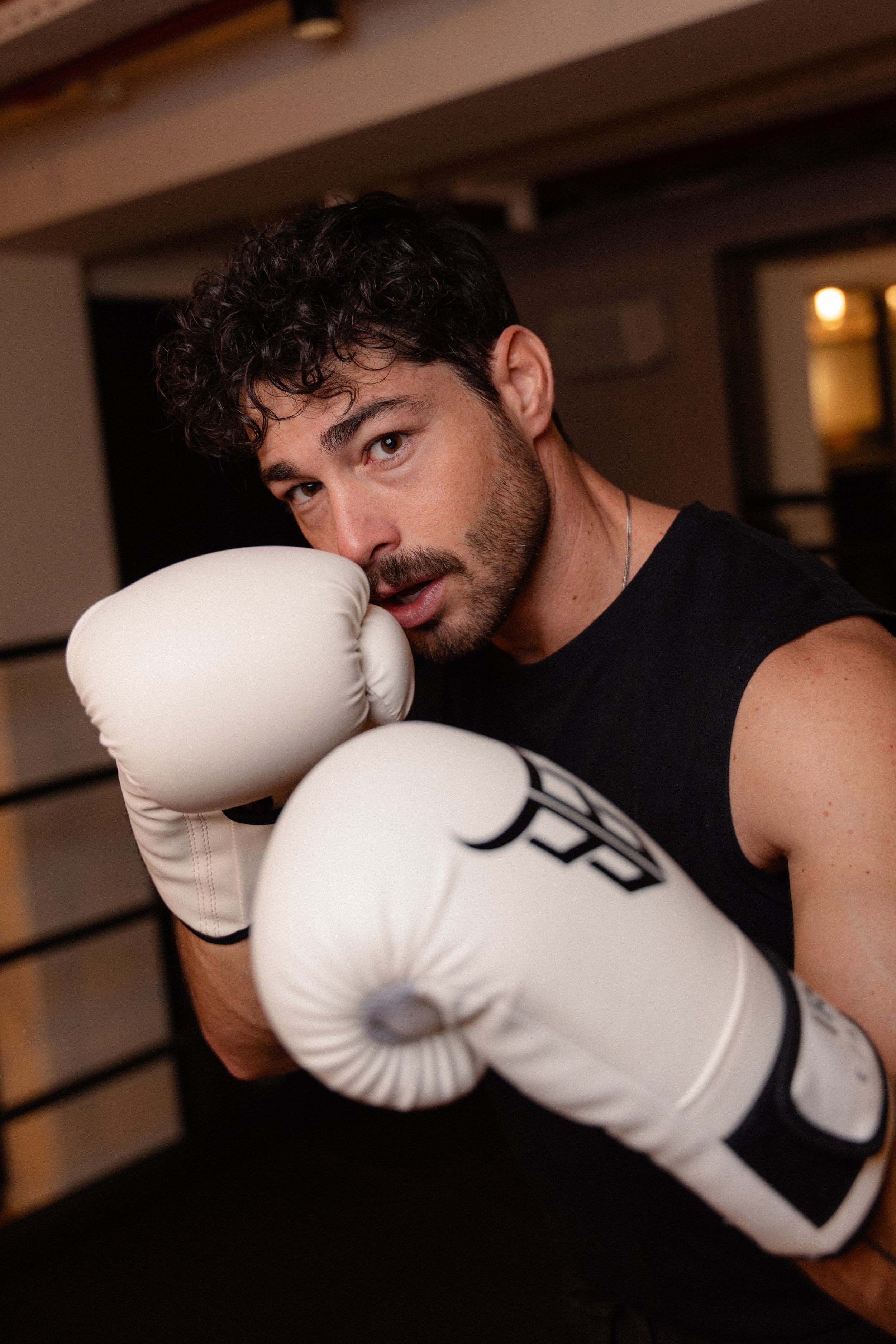 Homme avec des gants de boxe, prêt à combattre, dans une salle de sport