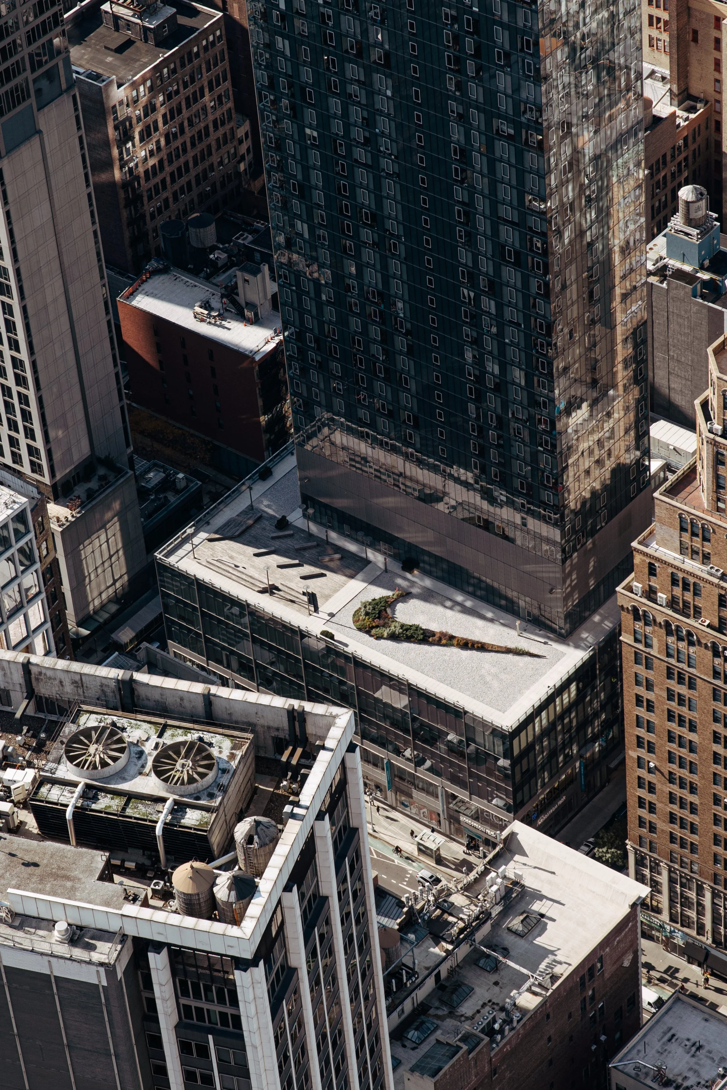 Photo aérienne de gratte-ciel modernes à New York, montrant des bâtiments en verre, en briques et des installations sur les toits.