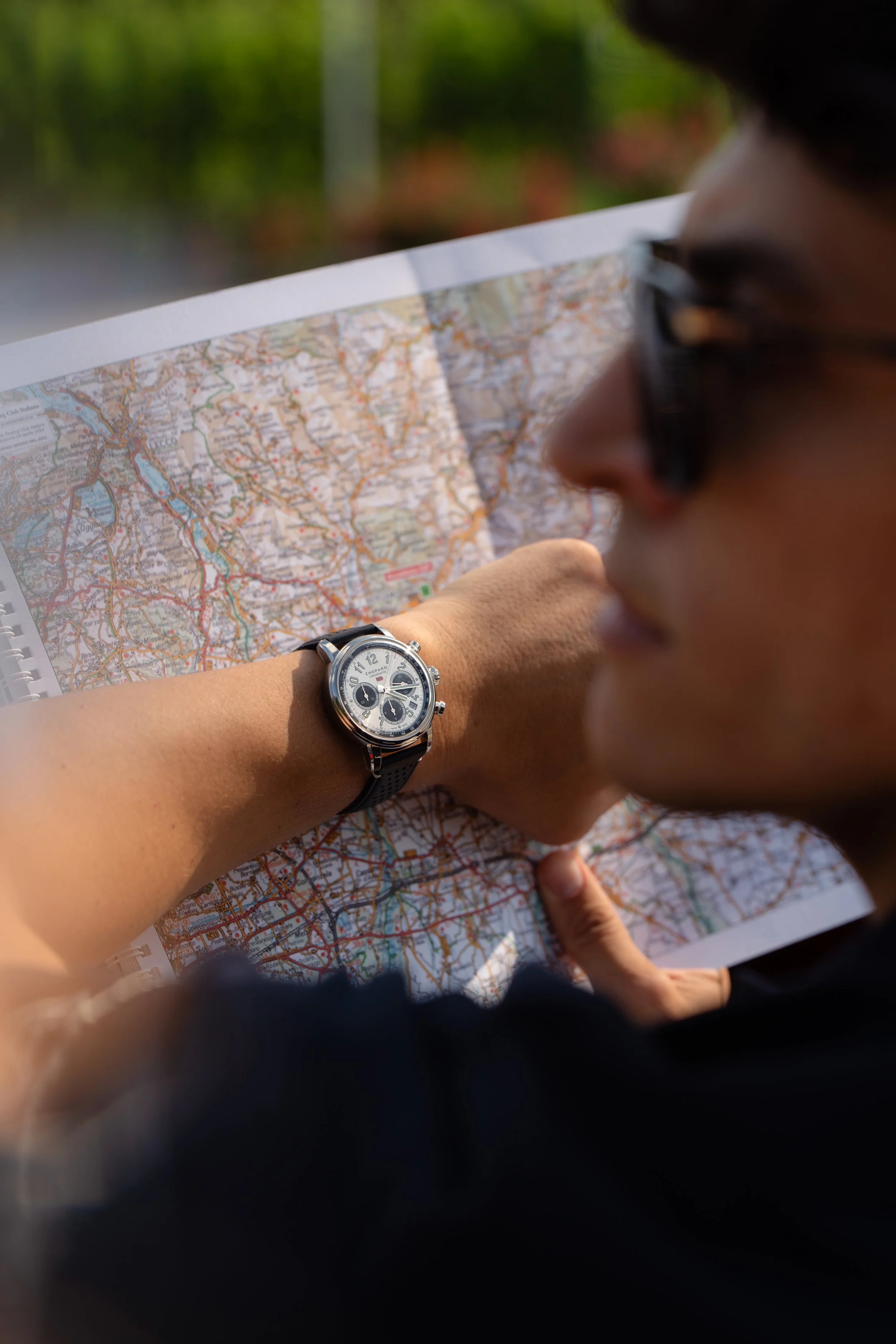 Un homme avec des lunettes regarde une carte routière, portant une montre noire à son poignet.