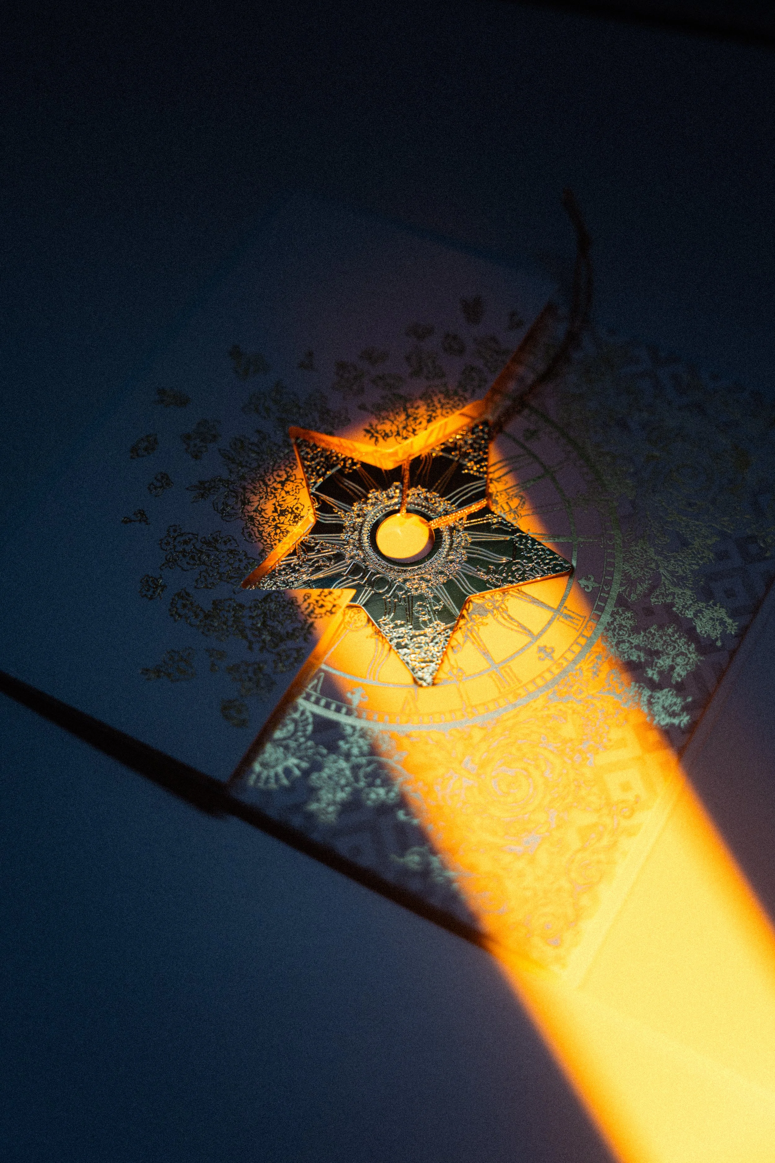 Une plaque de jeu de société avec un symbole d'étoile en métal, éclairée par une lumière orange, avec des détails complexes et un fond sombre.