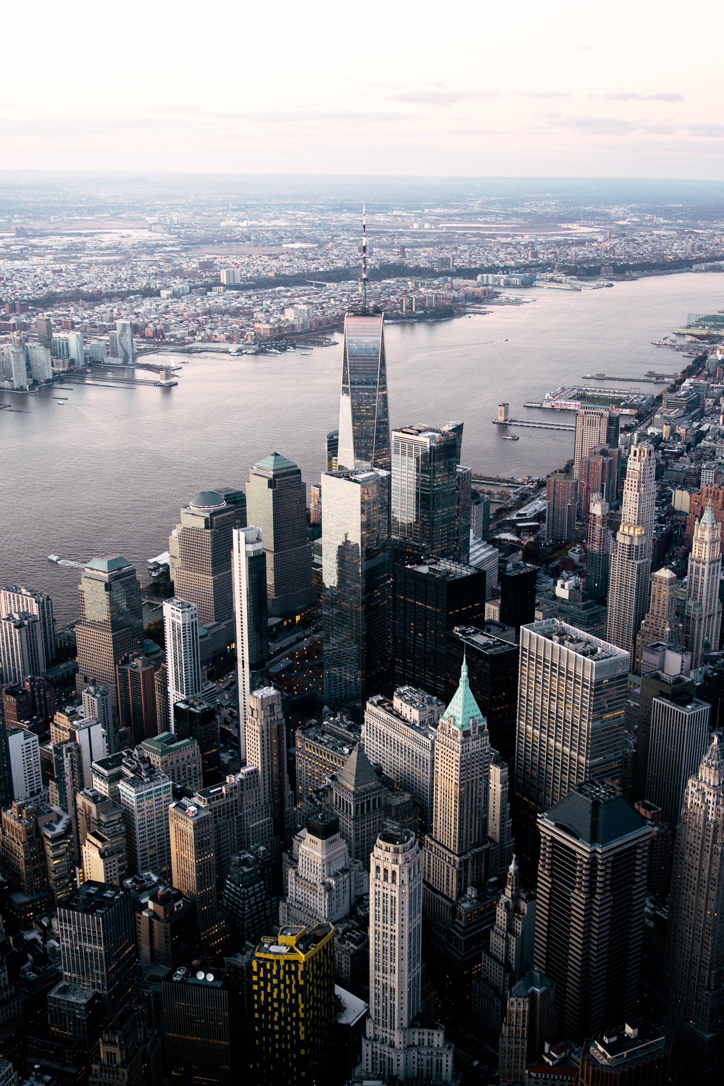 Vue aérienne de New York avec de nombreux gratte-ciel et la rivière Hudson en arrière-plan, en fin de journée.