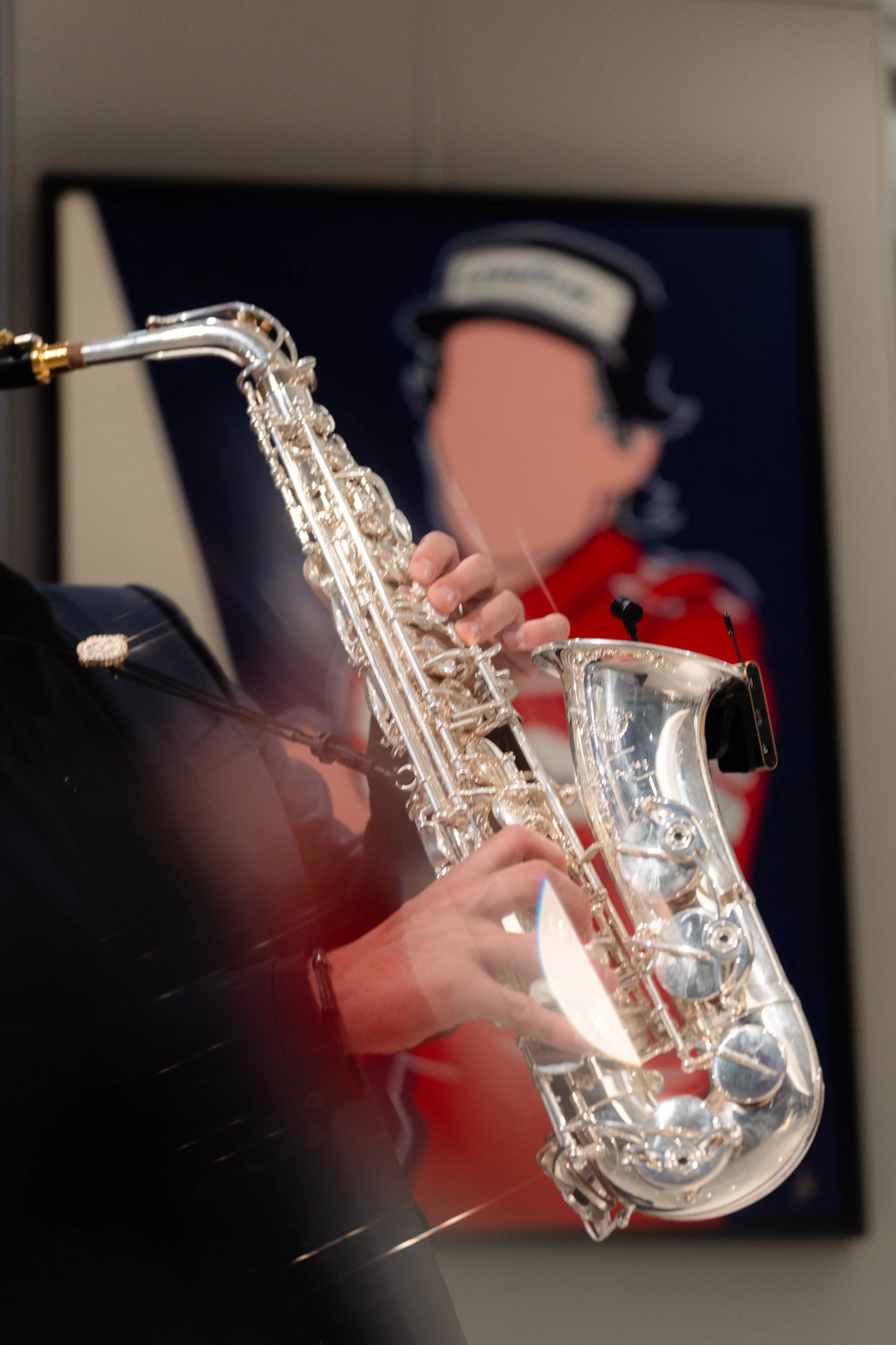 Un musicien joue du saxophone en focus, avec une peinture stylisée d'une personne en uniforme de marin en arrière-plan.