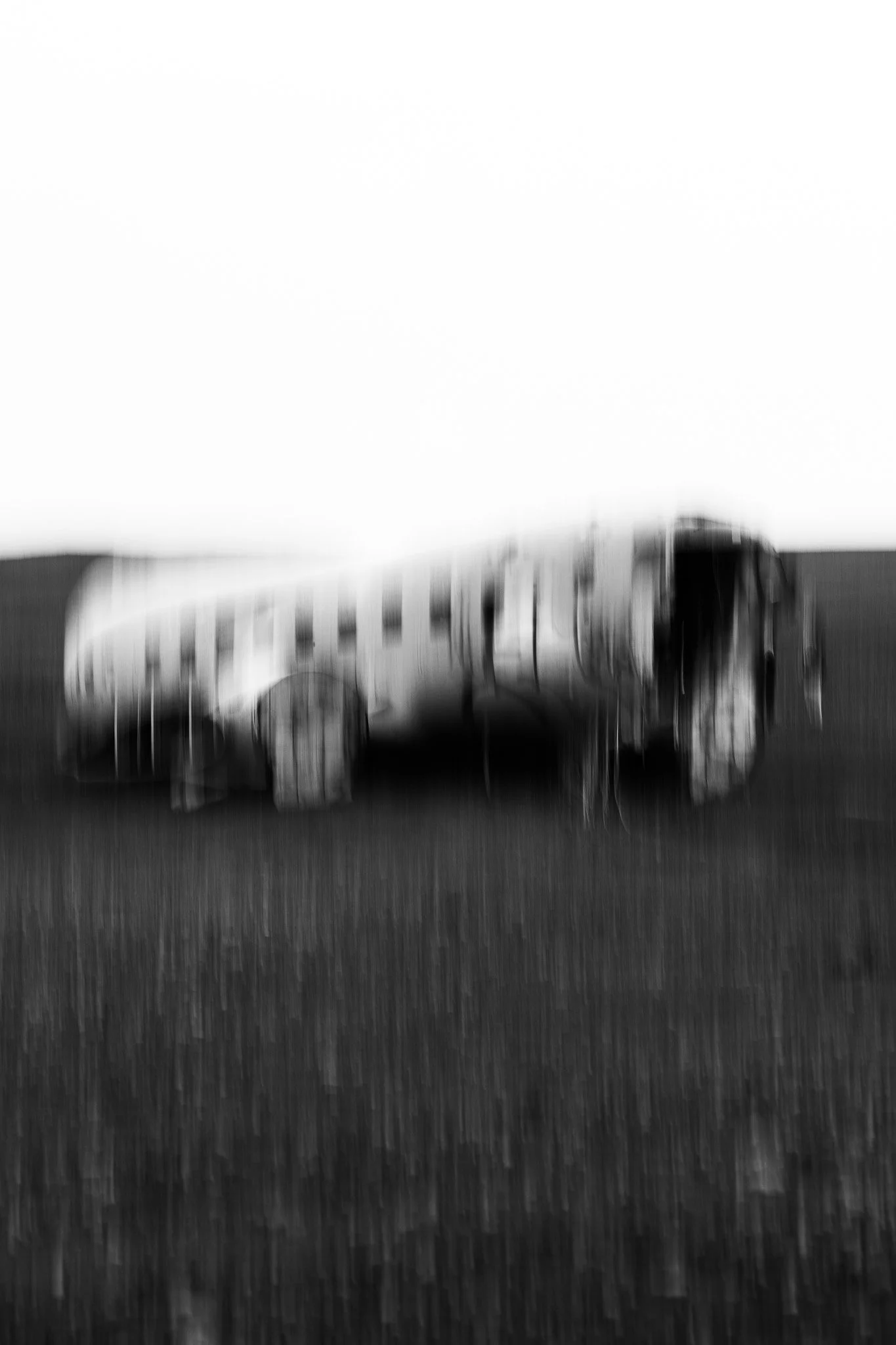 Une vieille voiture abandonnée dans un champ, image en noir et blanc avec un effet de flou. ISLANDE
