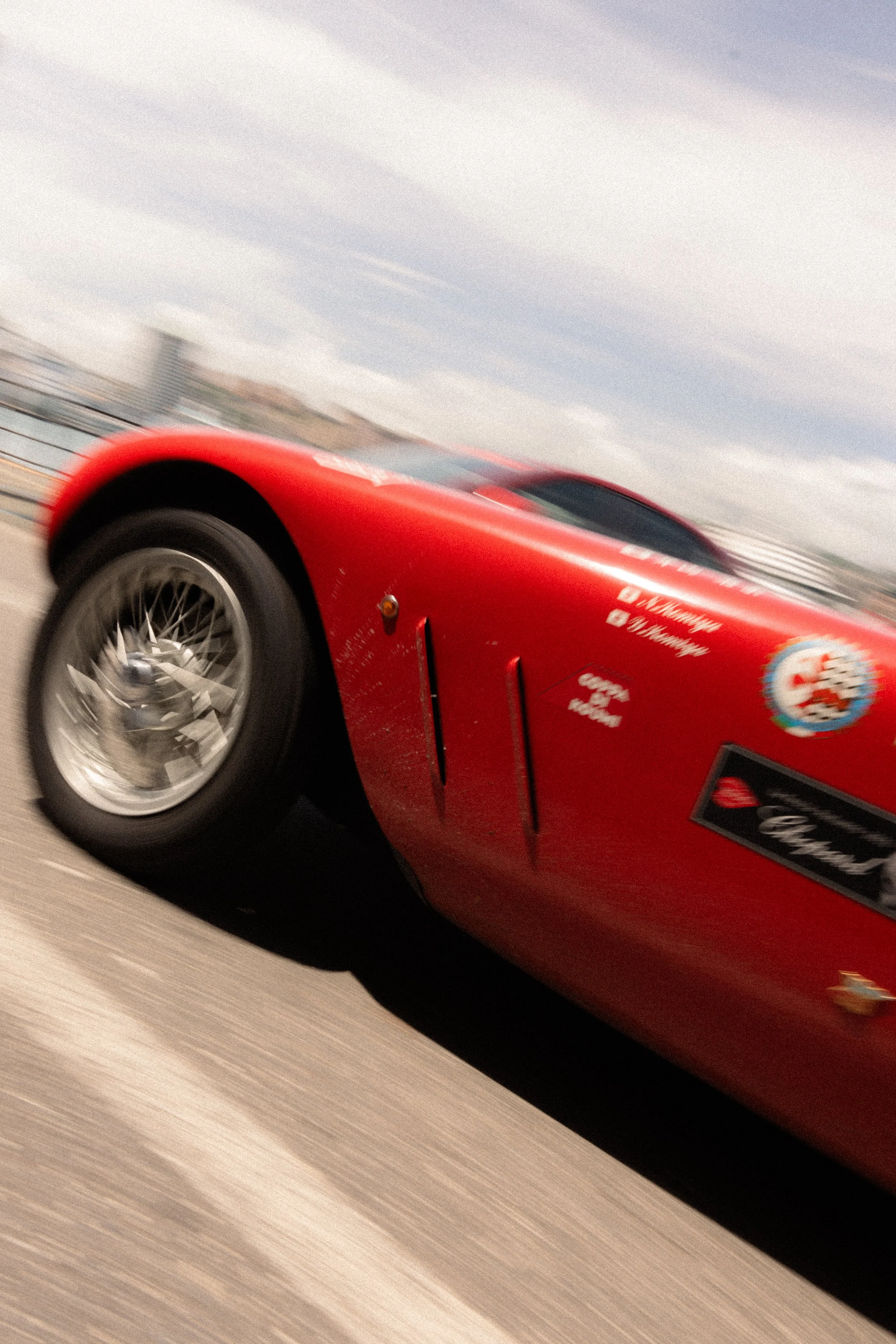 Voiture de course rouge en mouvement sur une piste, vue inclinée avec flou en arrière-plan.
