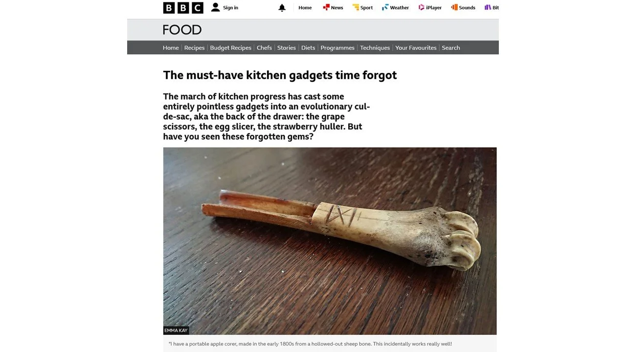 A small carved piece of bone shaped like a dog's paw, with slash marks on the handle, placed on a wooden surface.