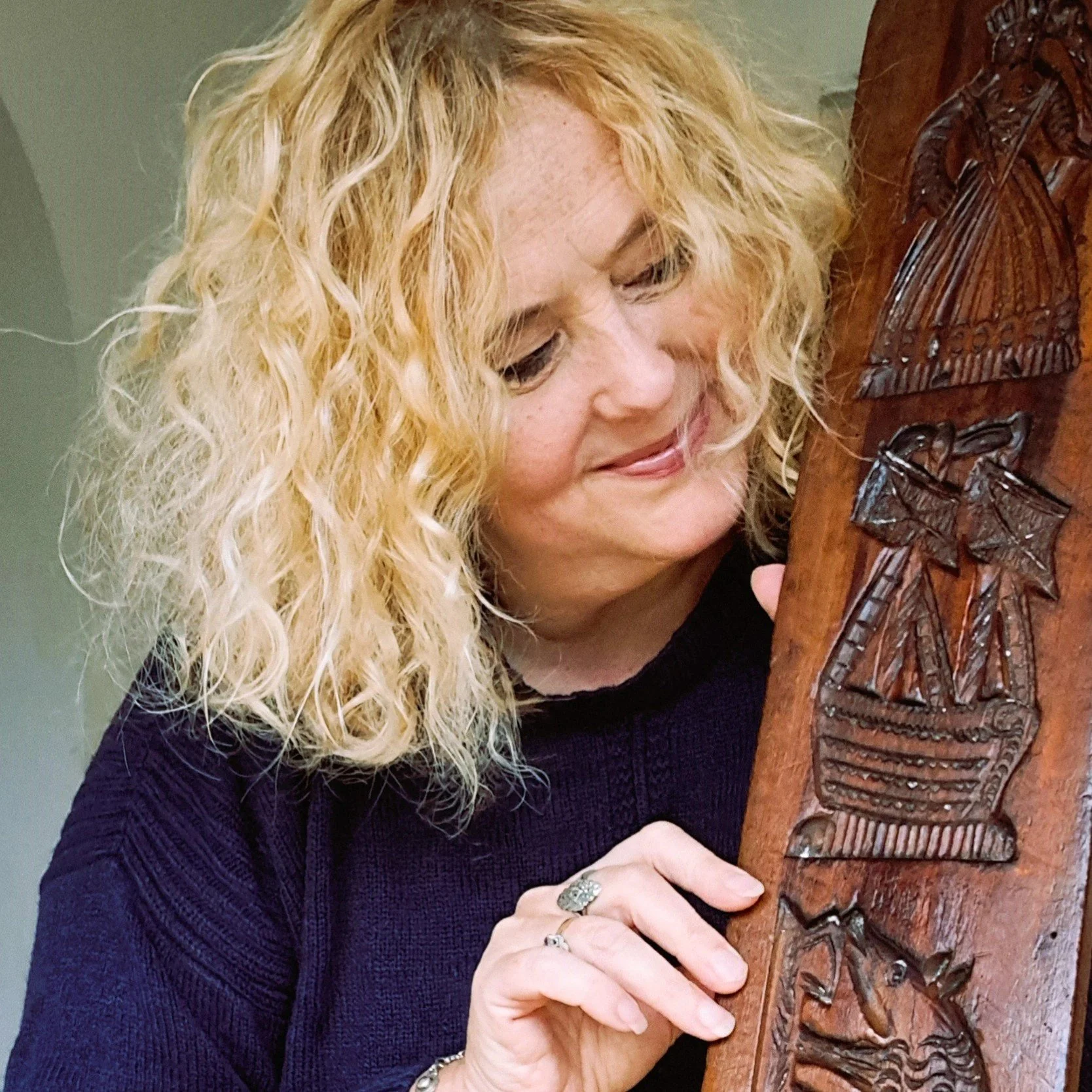 Historian Emma Kay examining carved wooden art.