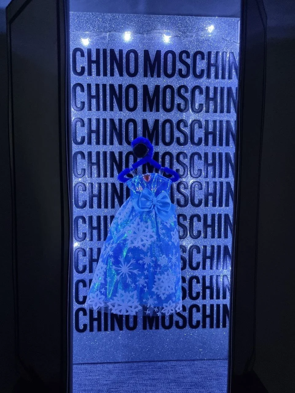 A doll dress was used in place of a full-scale garment to reinforce the Barbie-inspired narrative, transforming the display into a stylised fashion vignette rather than a conventional retail presentation.