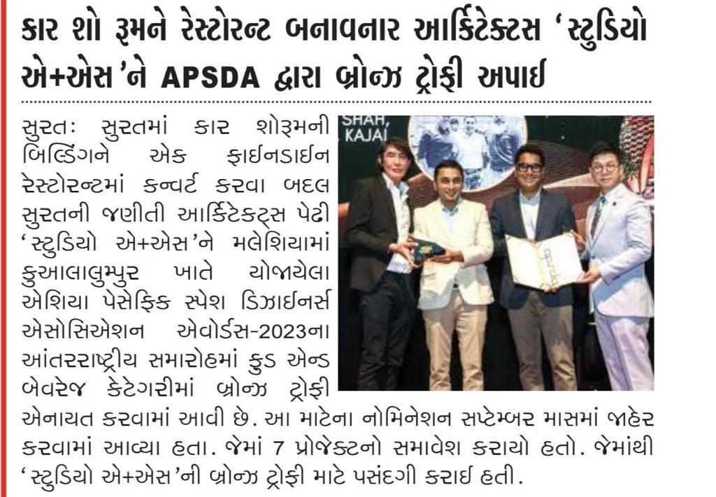 Group of four people on stage during award ceremony, holding awards and plaques, backdrop with text, all dressed in formal business attire.
