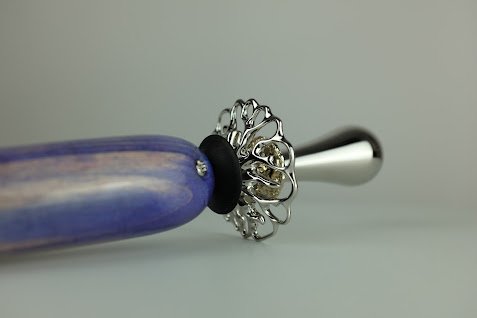 Un tournevis à tête plate avec une poignée violette et un embout en acier, placé contre un fond neutre.