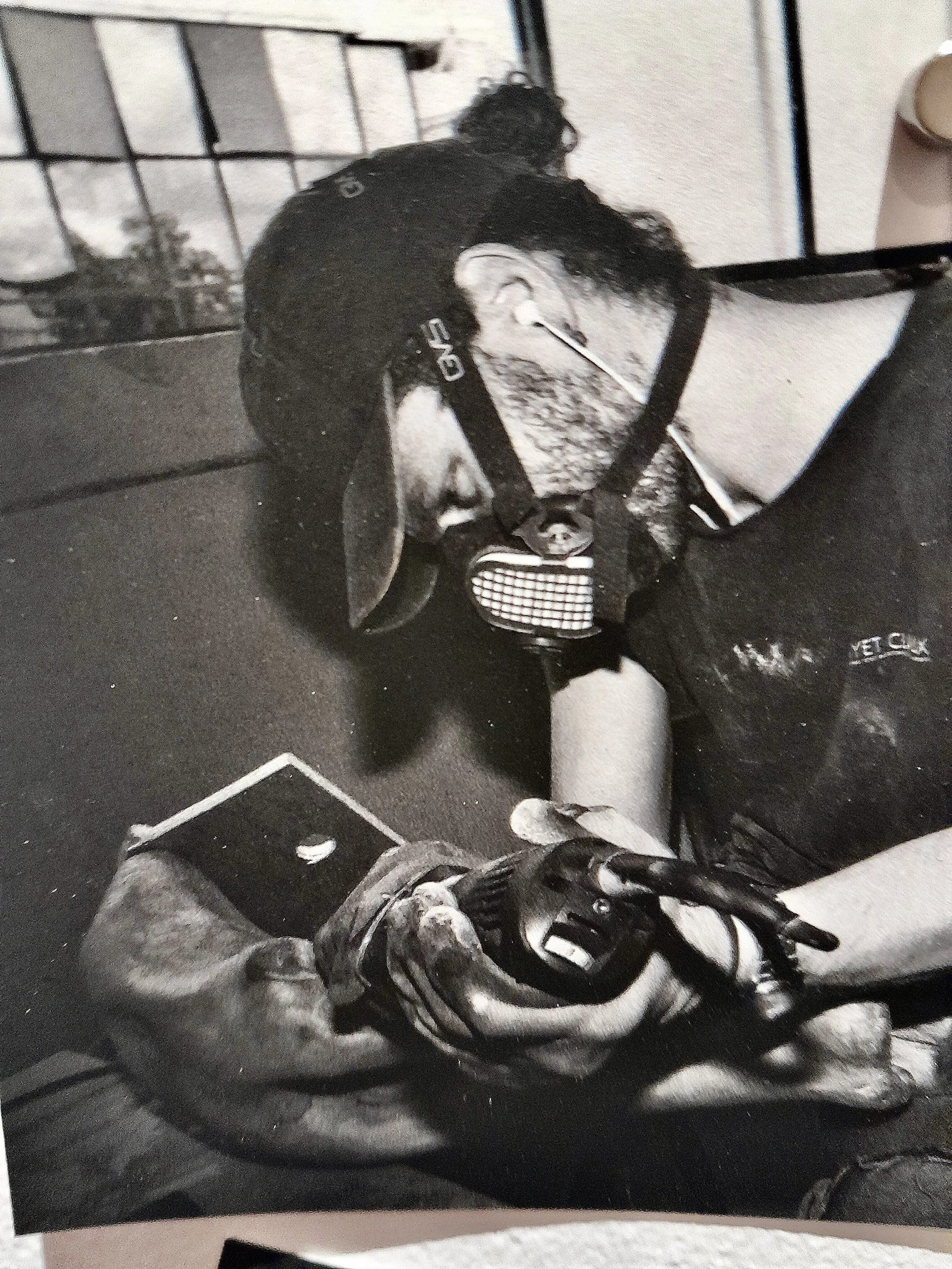 Un homme portant un masque de protection, un casque, une tenue de travail, et utilisant un outil électrique, est concentré sur une tâche manuelle.